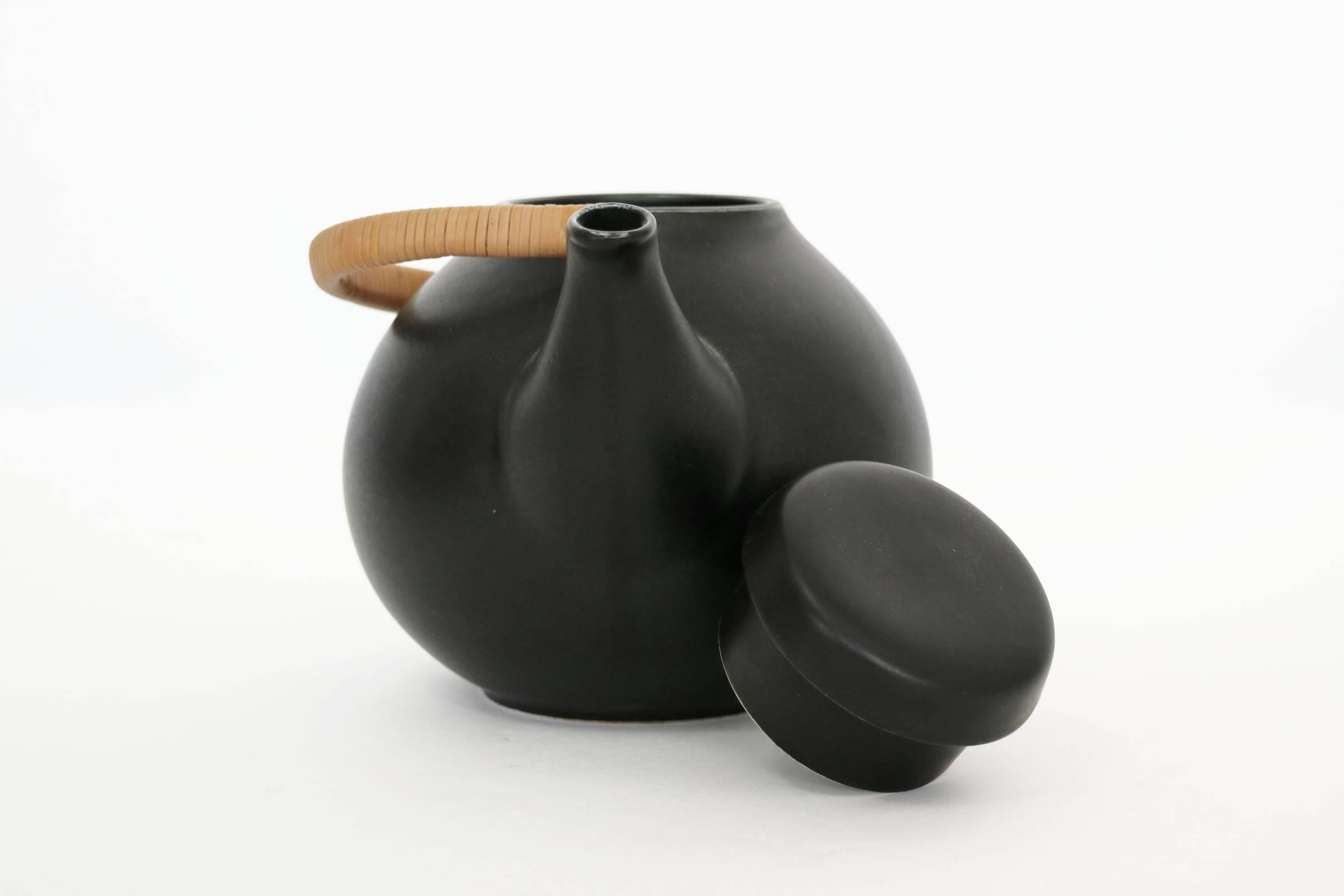 Glazed ceramic tea pot with caned handle. Marked 