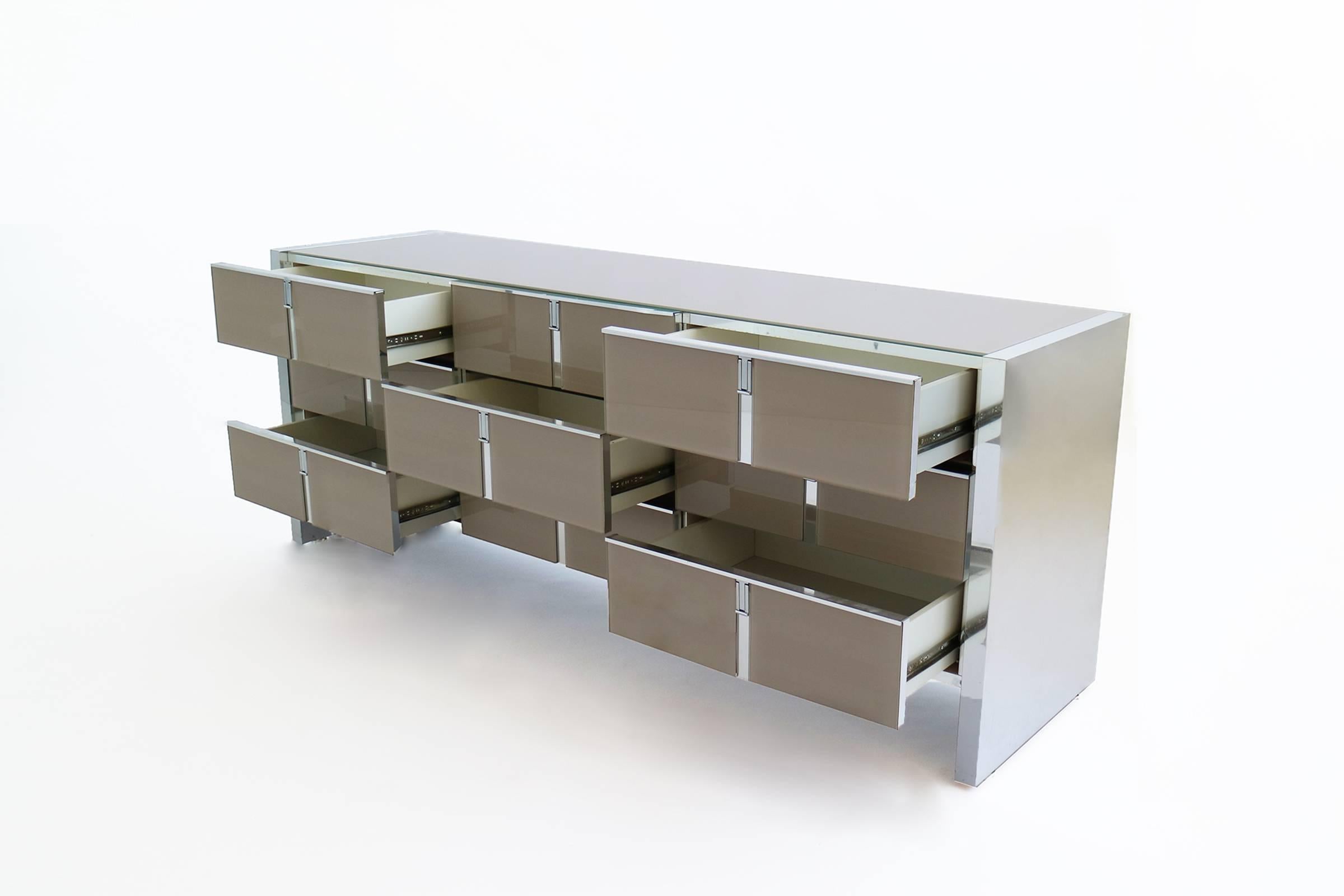 Chrome wrapped legs, with glass faced drawers and surface. Nine pull-out drawers.