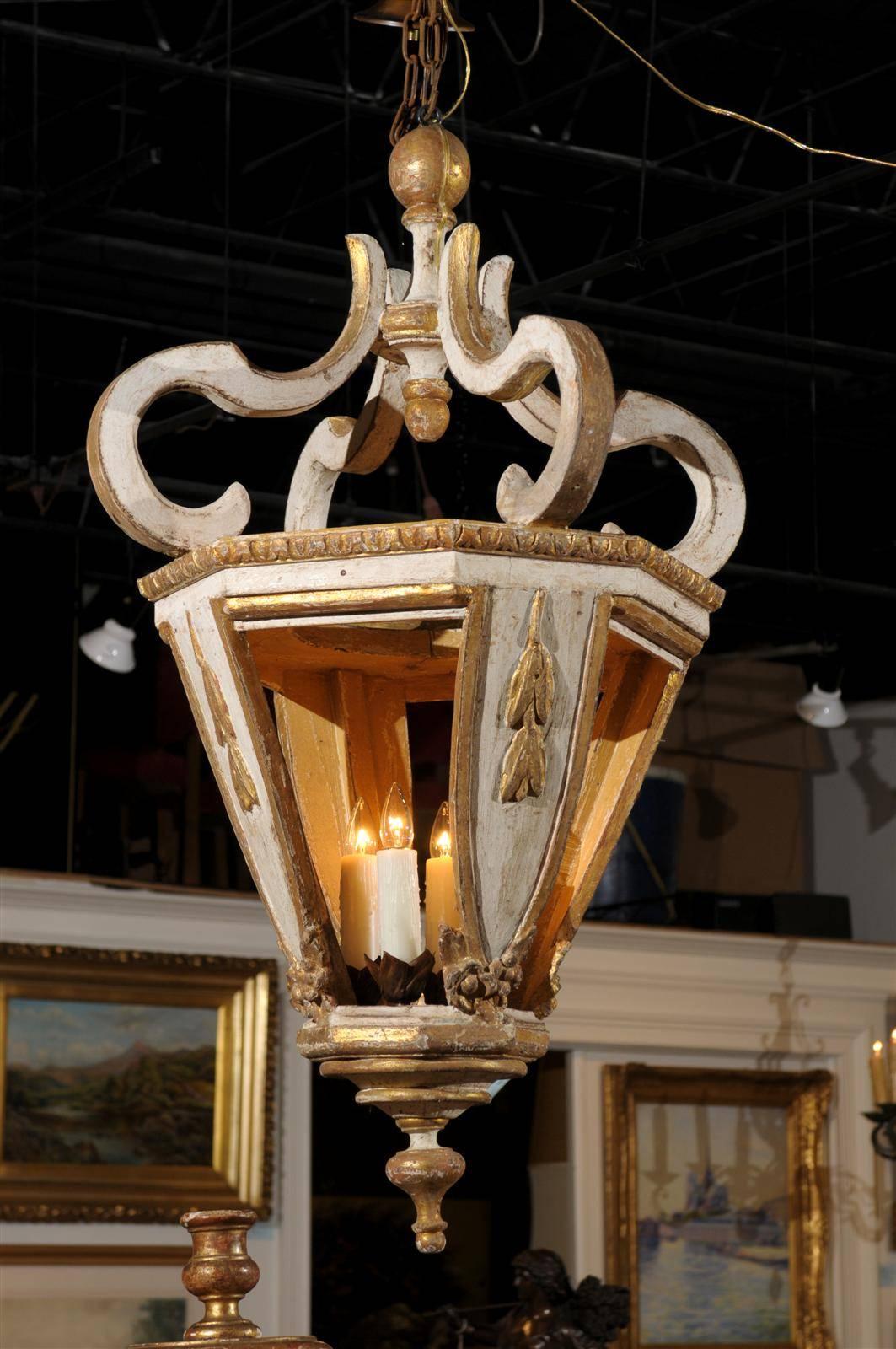 Baroque style large size Italian painted and gilded four-light hanging lanterns from the 19th century. Each of these spectacular giltwood lanterns features an octagonal body surmounted with baroque volutes terminated with round finials. The
