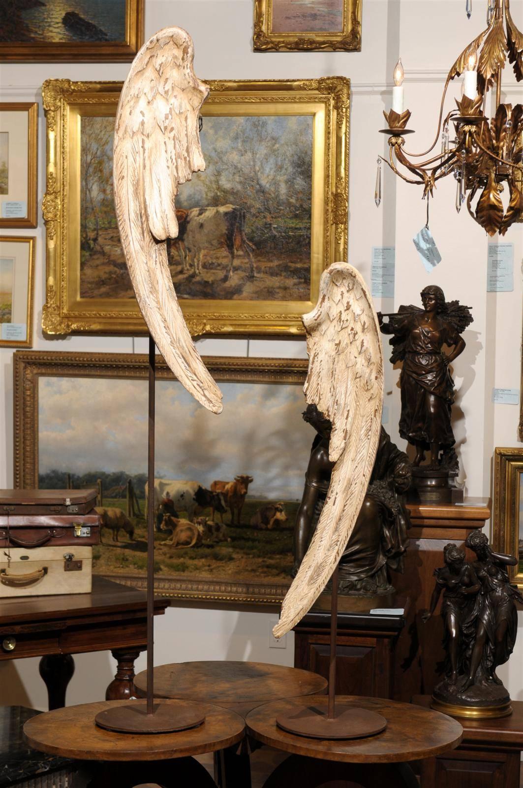 Pair of late 18th to early 19th century sculptural angel wings with unique patina, raised on iron stands of differing heights, with some original hardware still attached. These loops might have been used to attach the wings to a figure, perhaps on a