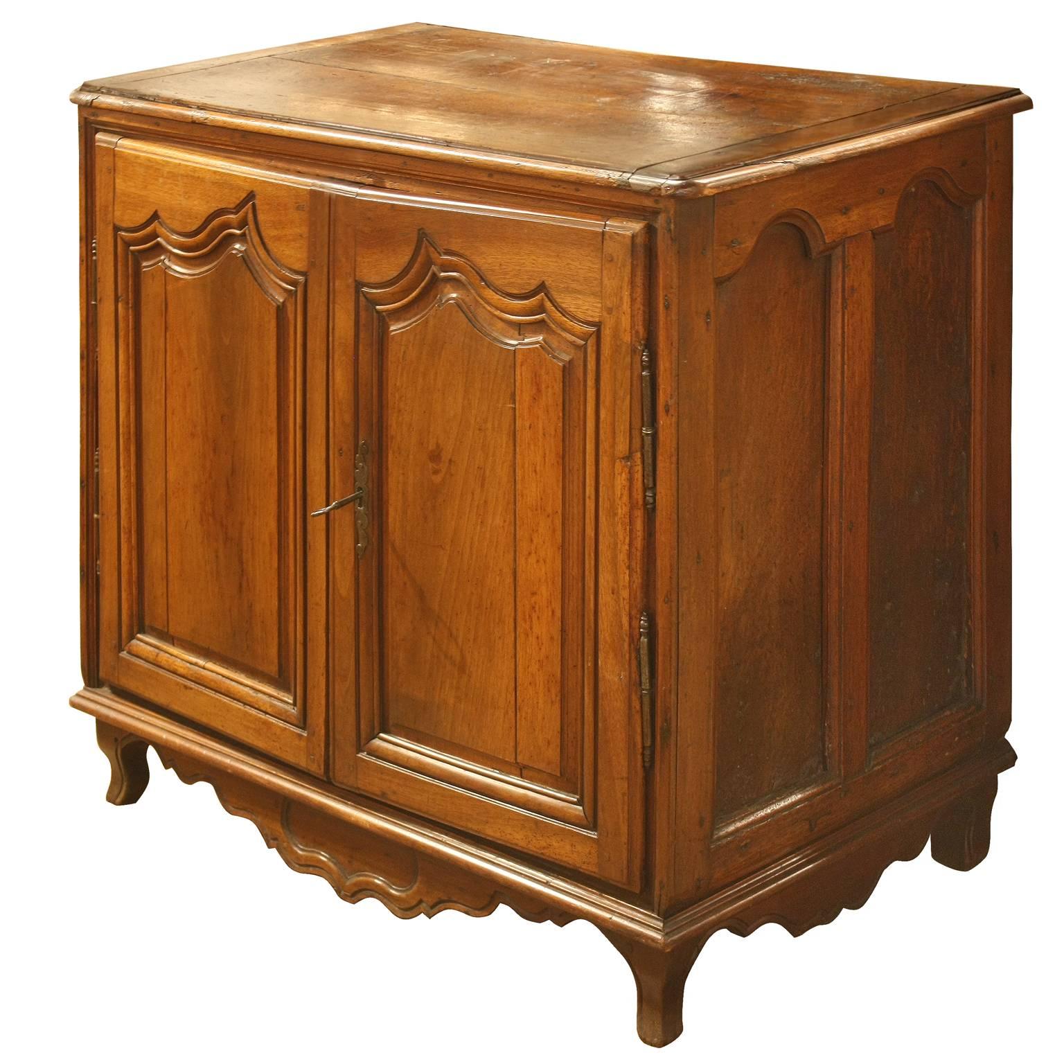 This French walnut commode from the second half of the 19th century will surprise you by its form. The piece is made of a rectangular top with rounded edge over two doors with carved motifs. A functioning key unlocks the right door while the left