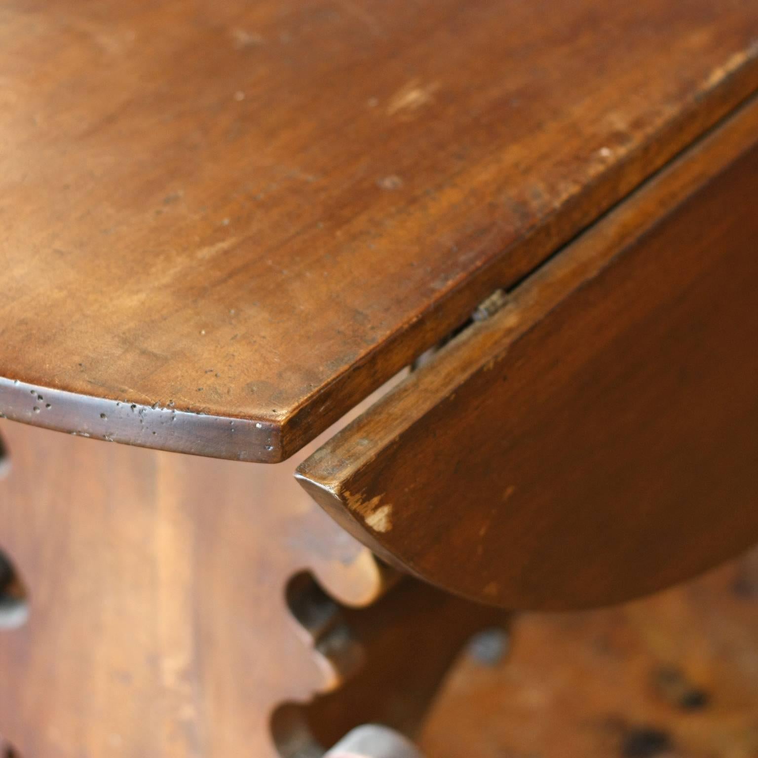 This Italian Florentine walnut medium size drop-leaf dining table from the early 18th century features an oval top over an exquisite Baroque style trestle base. The drop-leaves are supported by two butterfly wedges, hand-carved with delicate