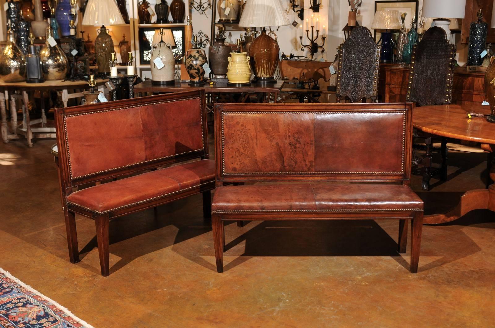 This English mahogany hall bench from the 19th century is fitted with leather on the backrest and seat, secured with a nailhead trim. The simple, rectangular back is raised on straight legs, while in front the seat rests on slightly tapered legs.