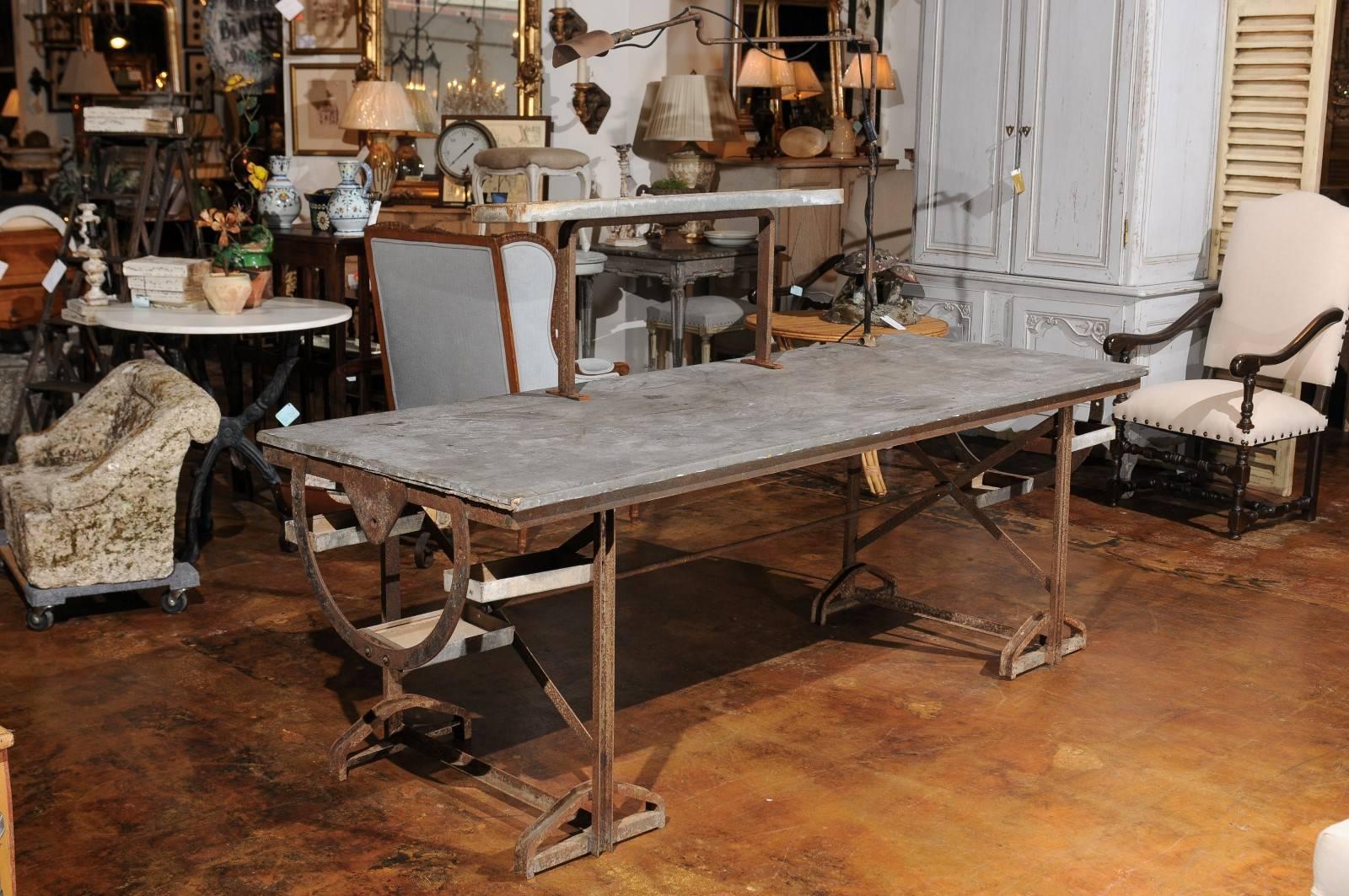 A French industrial two-tiered work table with iron armature and zinc top, task light and small shelves from the late 19th century. Born a few years after Emile Zola wrote some of his most famous novels featuring French workers from the second half