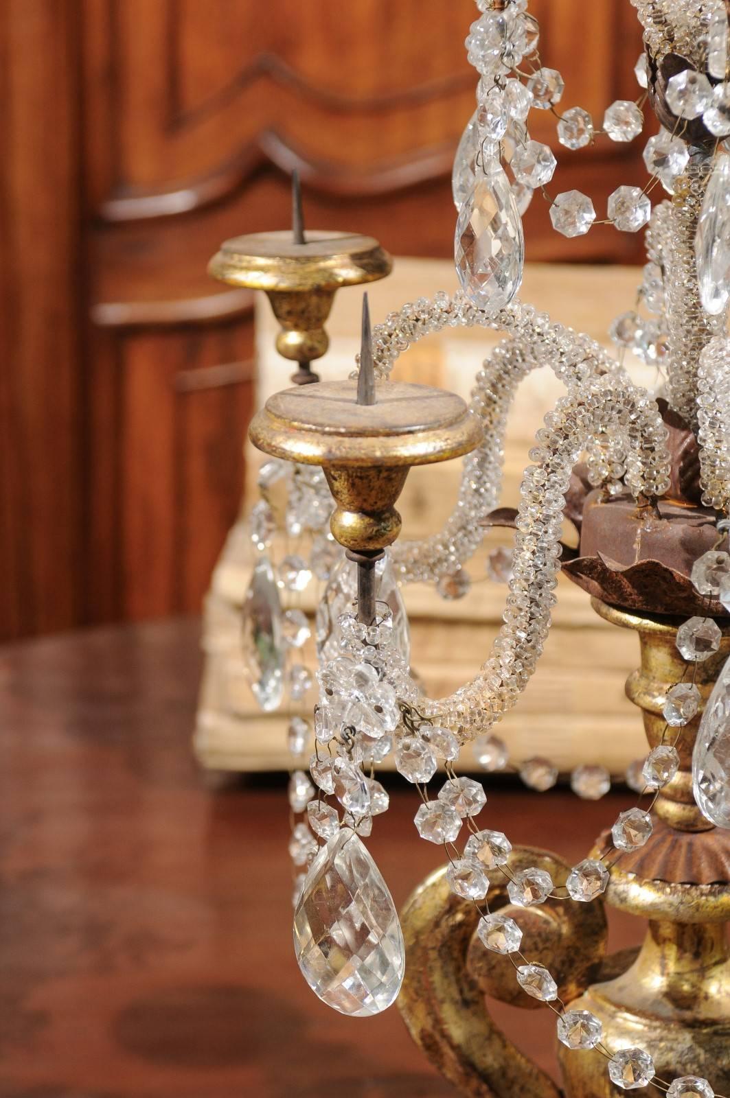 An Italian neoclassical style giltwood and crystal girandole from the late 19th century. This exquisite Italian candelabra features a neoclassical giltwood urn with oversized volute handles flanking a delicate body. Raised on a square shaped base,