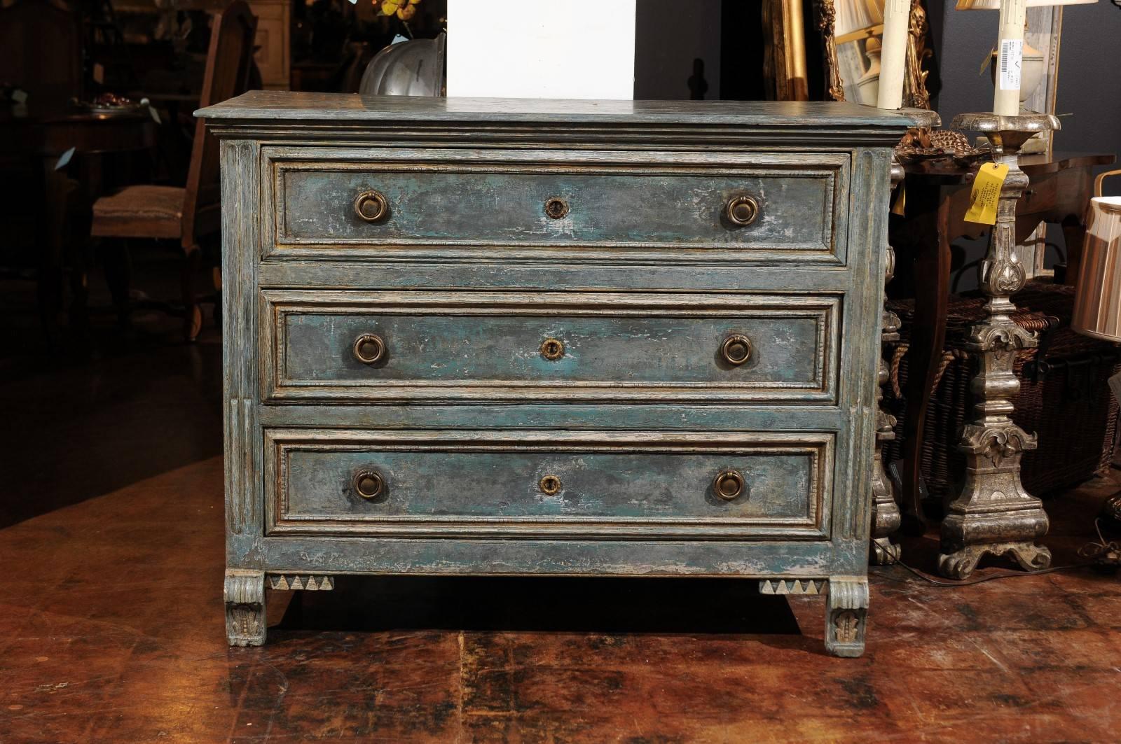 A Swedish neoclassical style blue painted pine three-drawer commode with console feet and fluted sides from the early 19th century. This Swedish painted chest features a marbleized rectangular planked top with rounded edges sitting above three