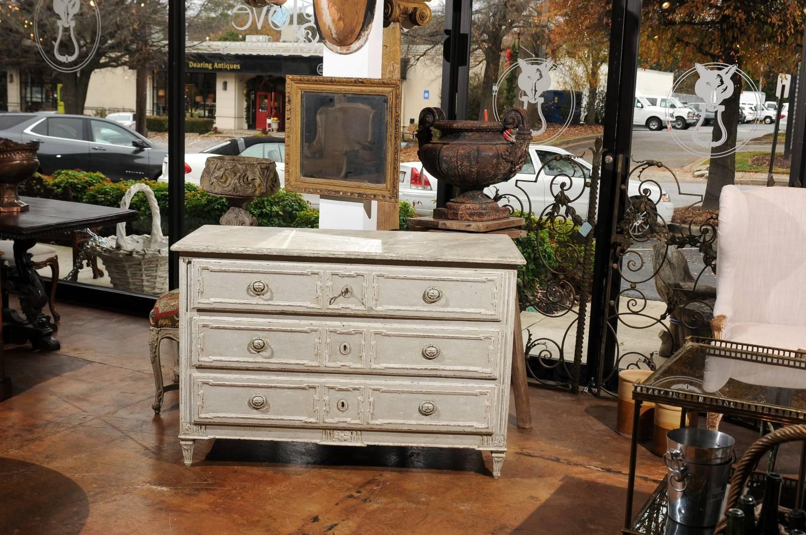 A French light grey painted pine three-drawer commode with marbleized top from the early 20th century. This French painted chest features a rectangular planked faux-marble top sitting above three long drawers. The painted hardware is beautifully