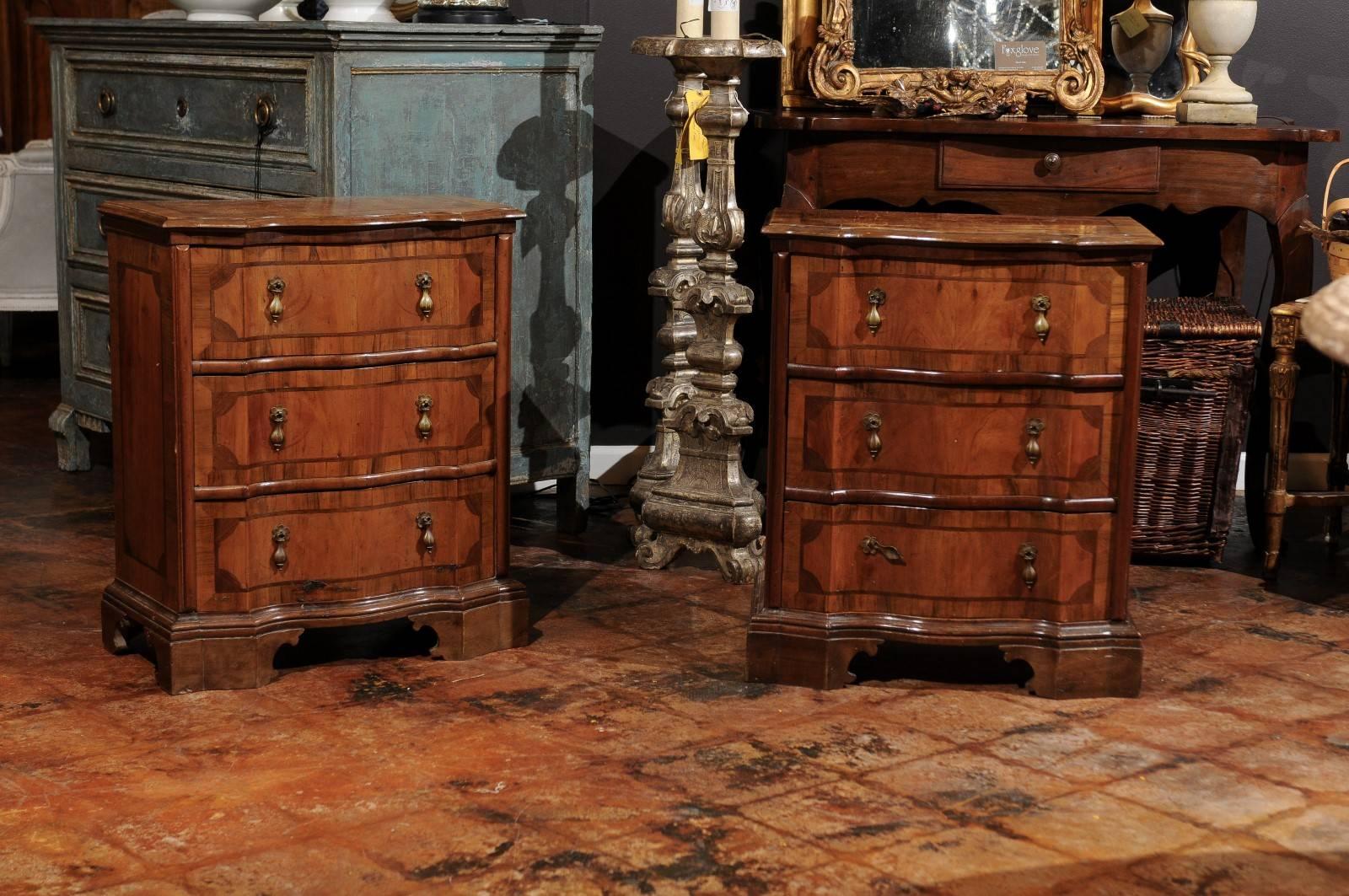 A pair of Italian walnut veneered three-drawer commodini with serpentine front and geometric inlay from the late 19th century. Born in the 1890s, each of this pair of Italian petite commodes features a shaped top with beveled edges, adorned with a