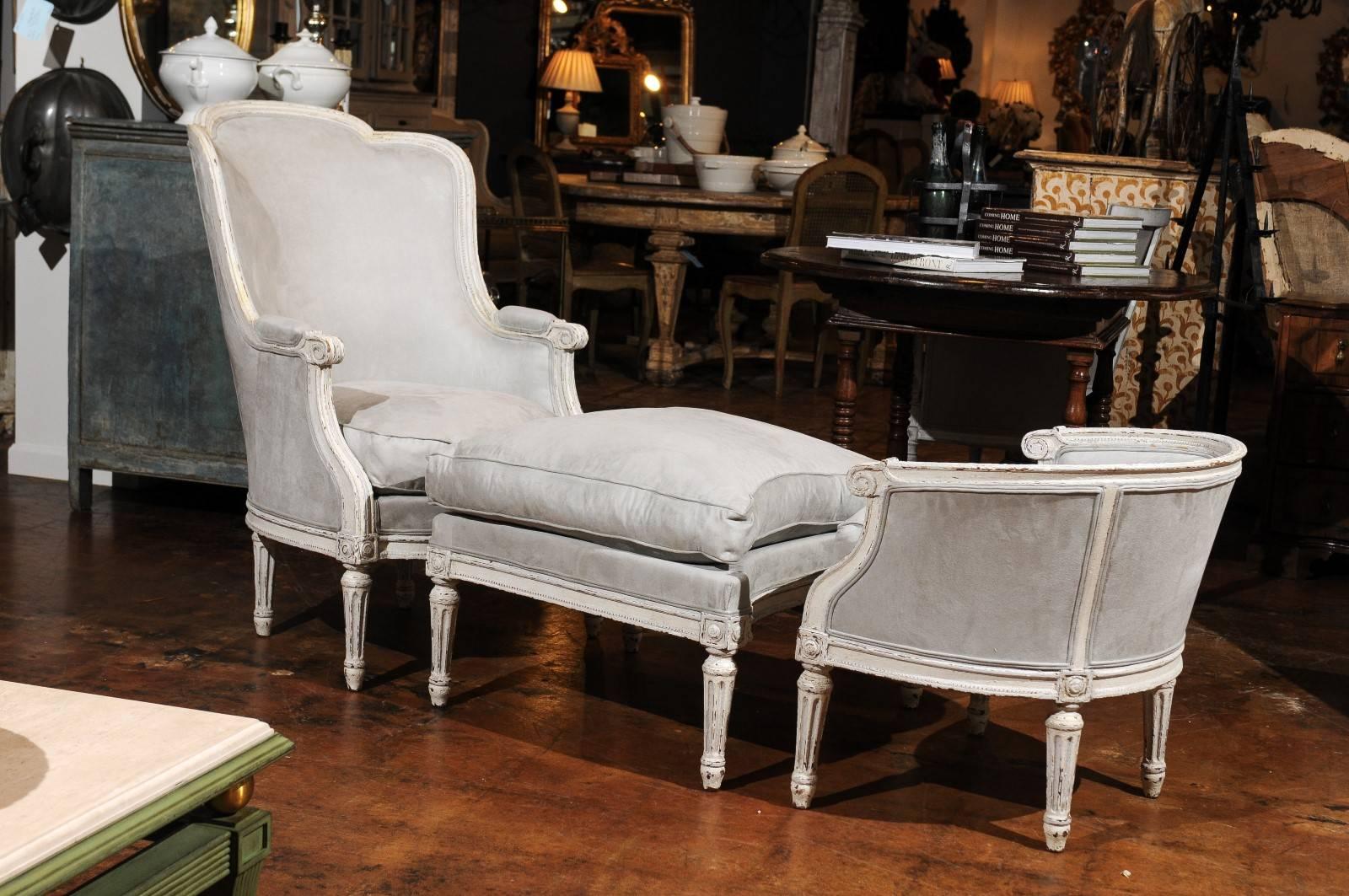 A French Louis XVI style off-white painted and re-upholstered 'Duchesse Brisée en Trois' with tall bergère, ottoman, tub chair and cushioned seats from the late 19th century. This French chaise longue features an exquisite bergère chair with curved