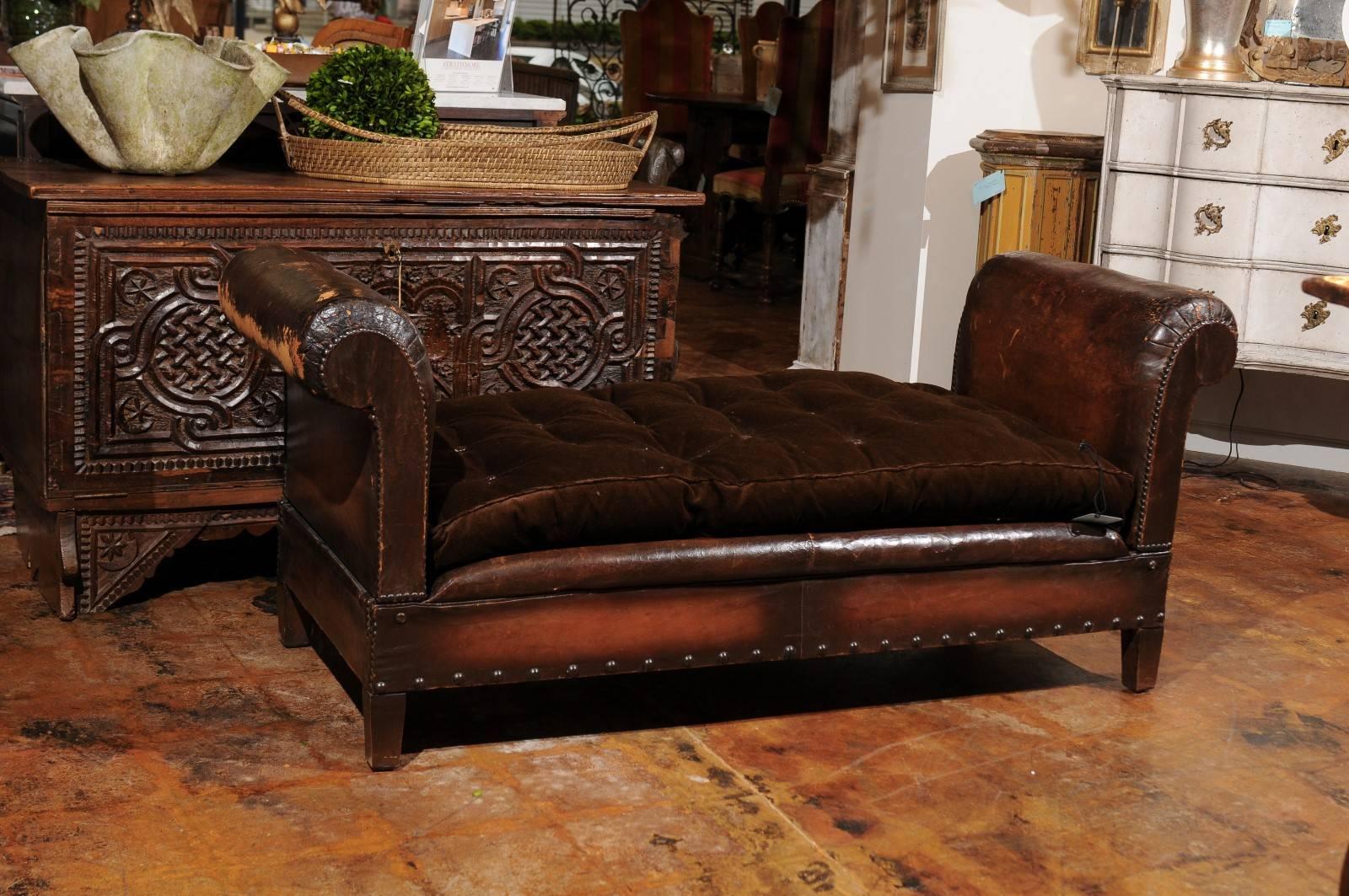 A French Turn of the Century leather backless bench with folding rolled arms from the late 19th, early 20th century. Born during the Belle Epoque, this French brown leather bench features two scrolled arms that fold down, conveniently allowing the