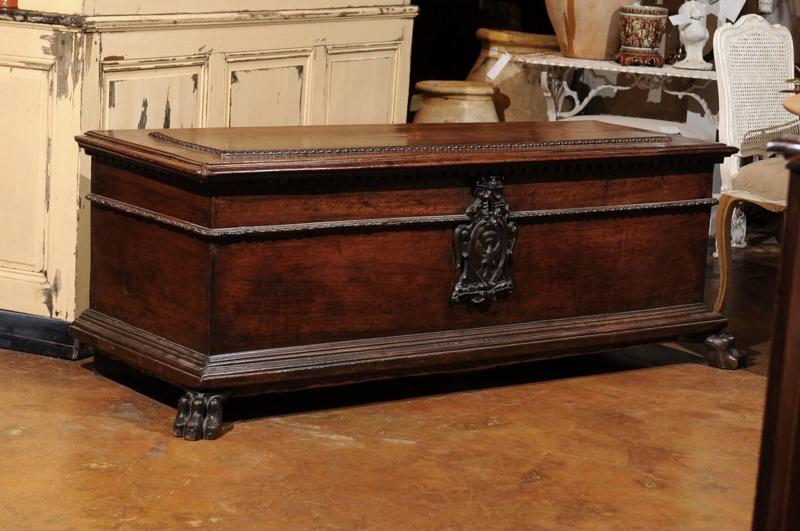 An Italian early 19th century wooden cassone chest with family crest, dentil molding and lion paw feet. Cassone chests were traditionally given as wedding gifts and were part of the bridal suite. As such, they were very prized possessions and in our
