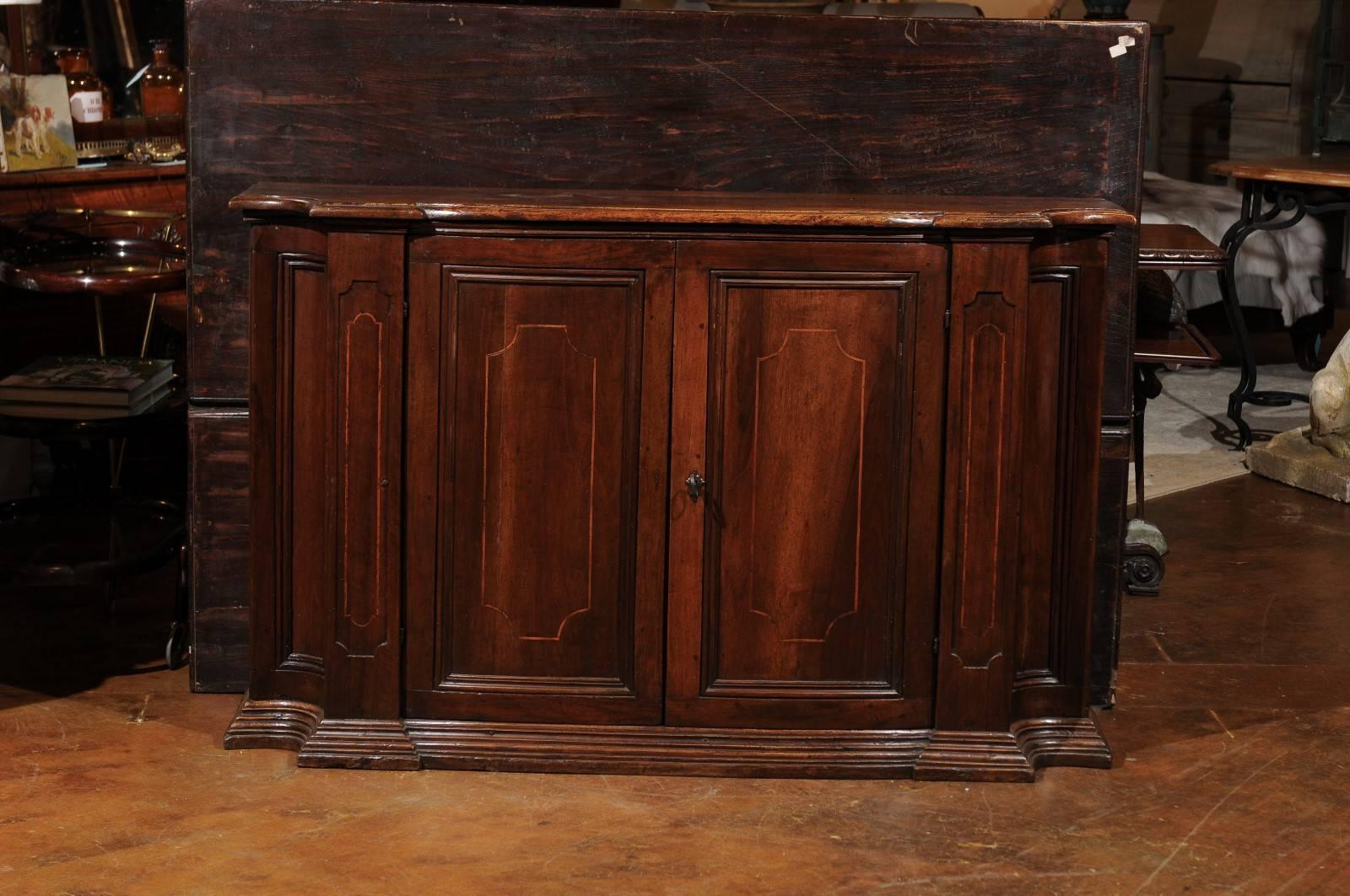 An Italian two-door mahogany buffet with inlaid banding, curved sides and molded plinth from the late 19th century. This Italian buffet features a shaped top with rounded edges sitting above an exquisitely designed facade. Two central doors with