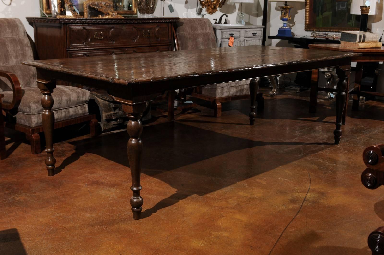 A contemporary custom-made American farm table with turned legs that can be made in any size. This dining room table features a rectangular planked top with knotted edges sitting above a bracketed apron delicately outlined by a thin molding. The
