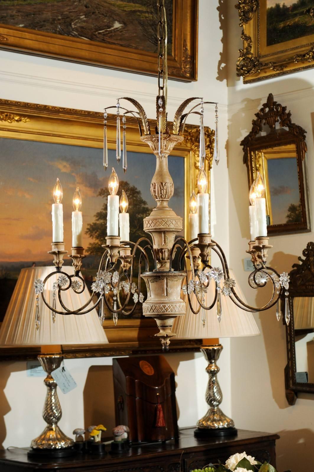 An Italian wood and gilt metal eight-light chandelier with central column, discreet crystals and foliage motifs from the late 19th century. This Italian chandelier features a central wooden column, carved with waterleaves and cross motifs, topped