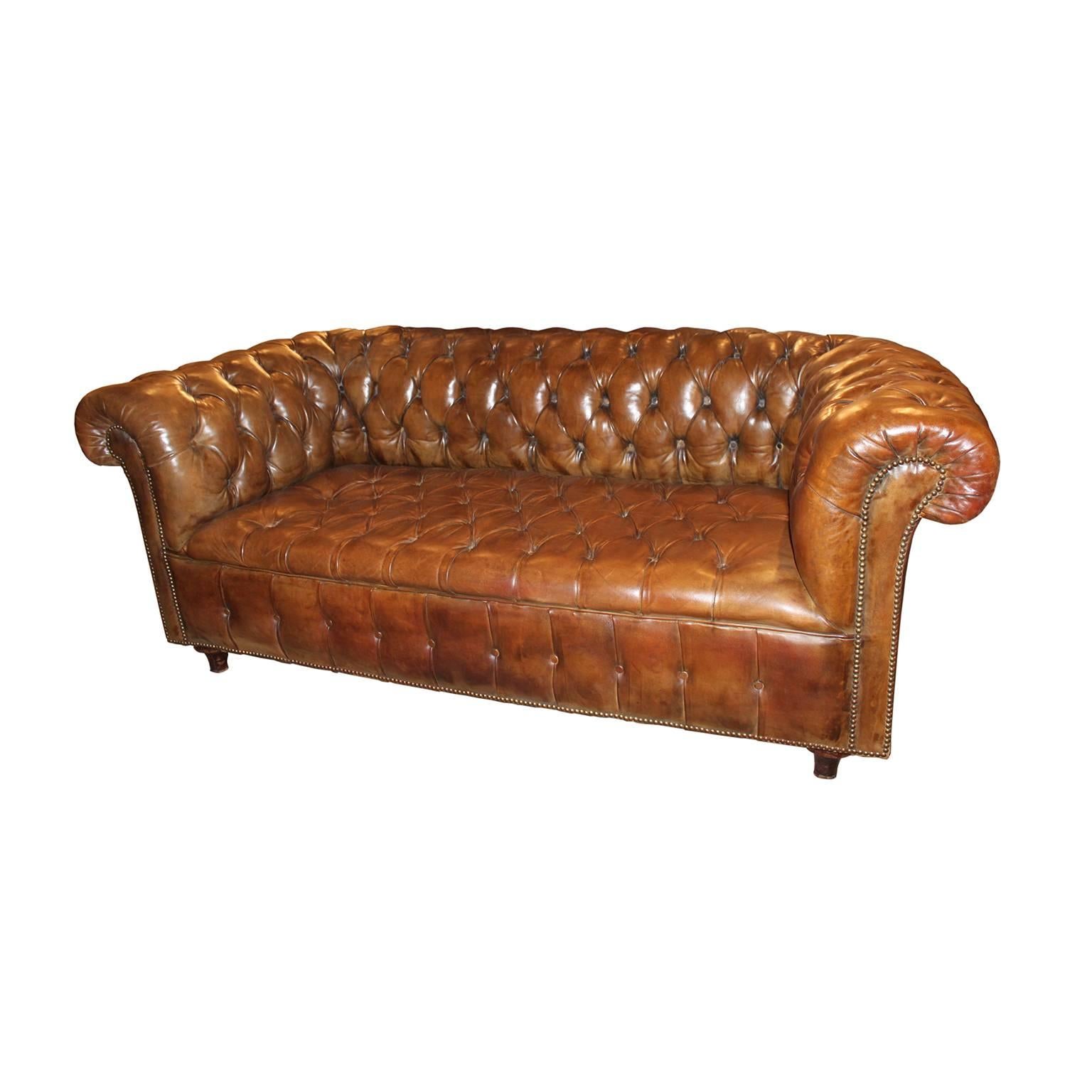 Chesterfield light brown leather tufted wingback sofa with all-over nail head trim.
