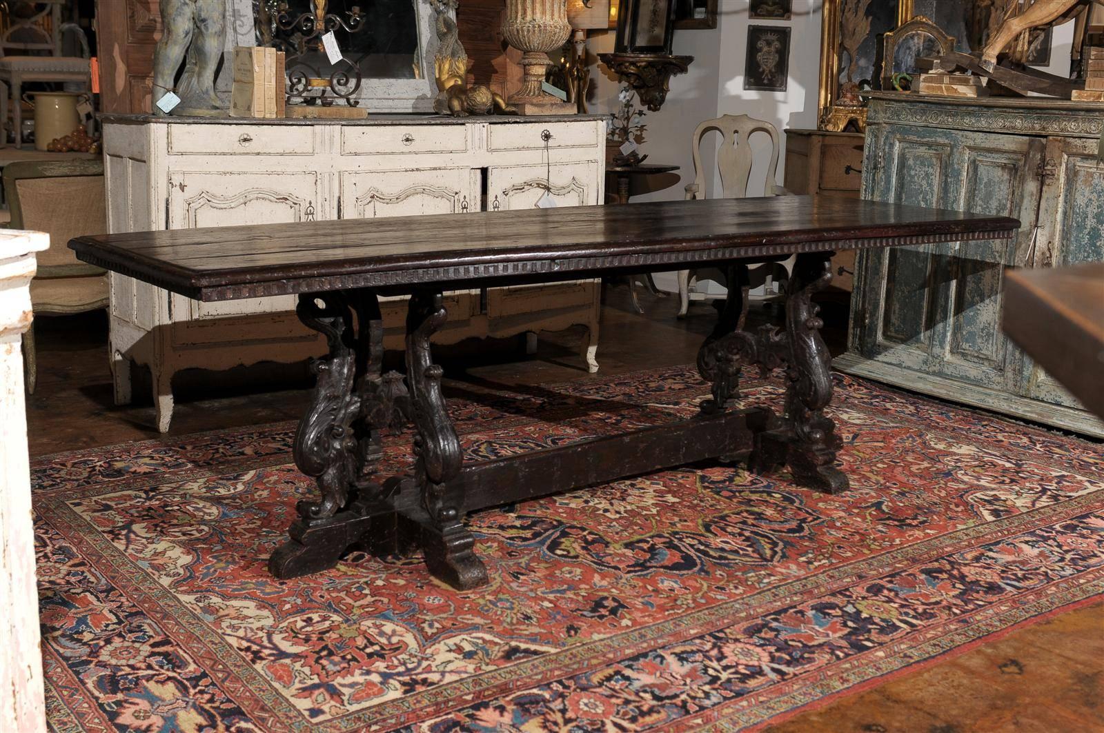 An Italian Baroque style carved oak library table with volute legs and stretcher from the early to mid 19th century. This Italian library table from the first half of the 19th century features a rectangular top with rounded edge and symmetrically