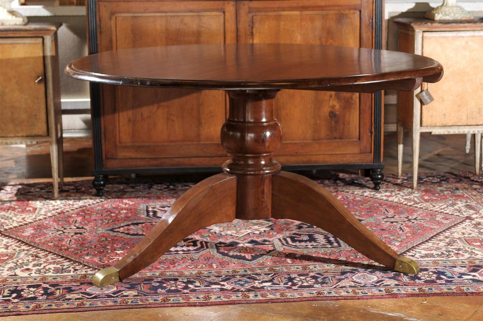 Italian walnut dining table with circular tilt top and pedestal base from the turn of the century. This Italian early 20th century walnut table features a round tilt top over a cylindrical turned pedestal base, raised on three splayed feet with