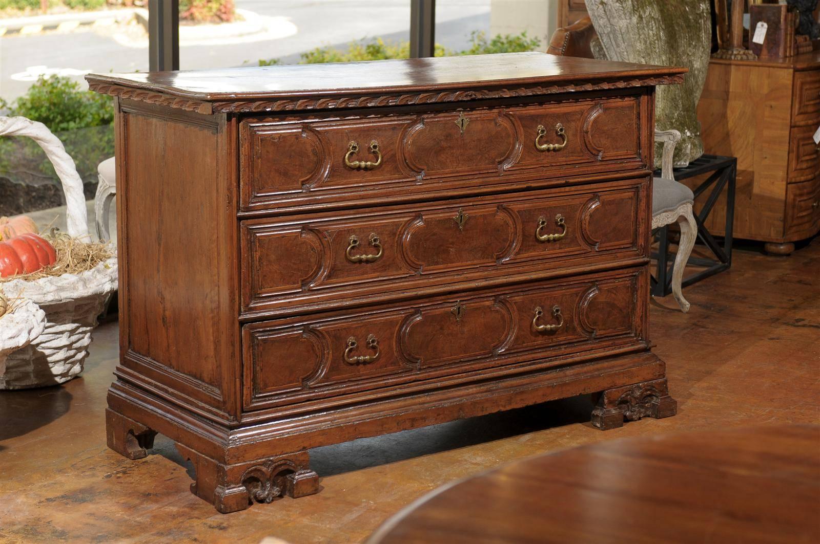 A tall Italian late 18th century carved three-drawer commode with unusual bracket feet. This Italian Neoclassical commode features a rectangular top with a skillfully carved frieze over three geometrical front drawers. Showing perfect symmetry and