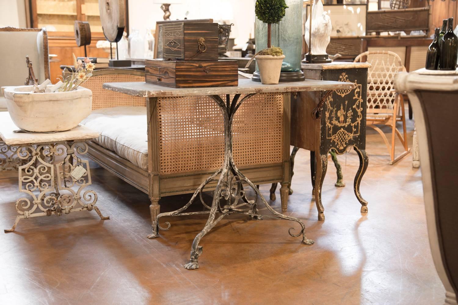 This French garden table with unusual rectangular top from the early 20th century was born in Arras, a city located in Northern France. The table is supported by a palm-tree shaped base at the top, ending its course gracefully with a quadripod base,