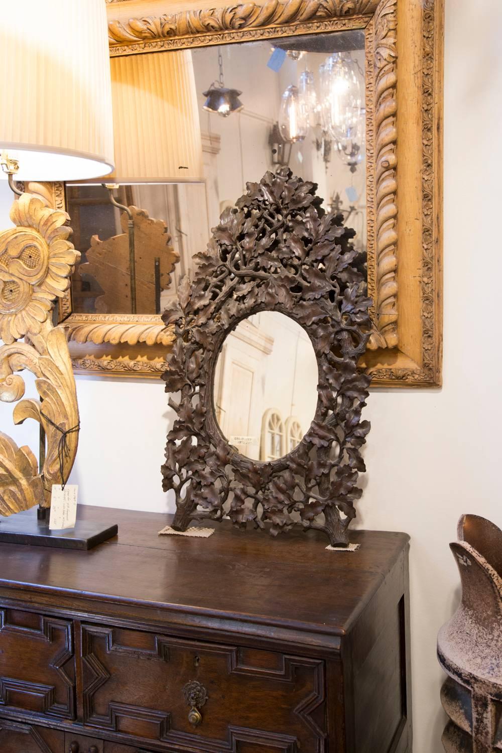 This elaborately carved French Black Forest oak mirror from the 19th century is made of a central oval clear glass mirror. Our eye however, is immediately drawn to the beautifully detailed frame, made of oak leaves attached to their branches. Its