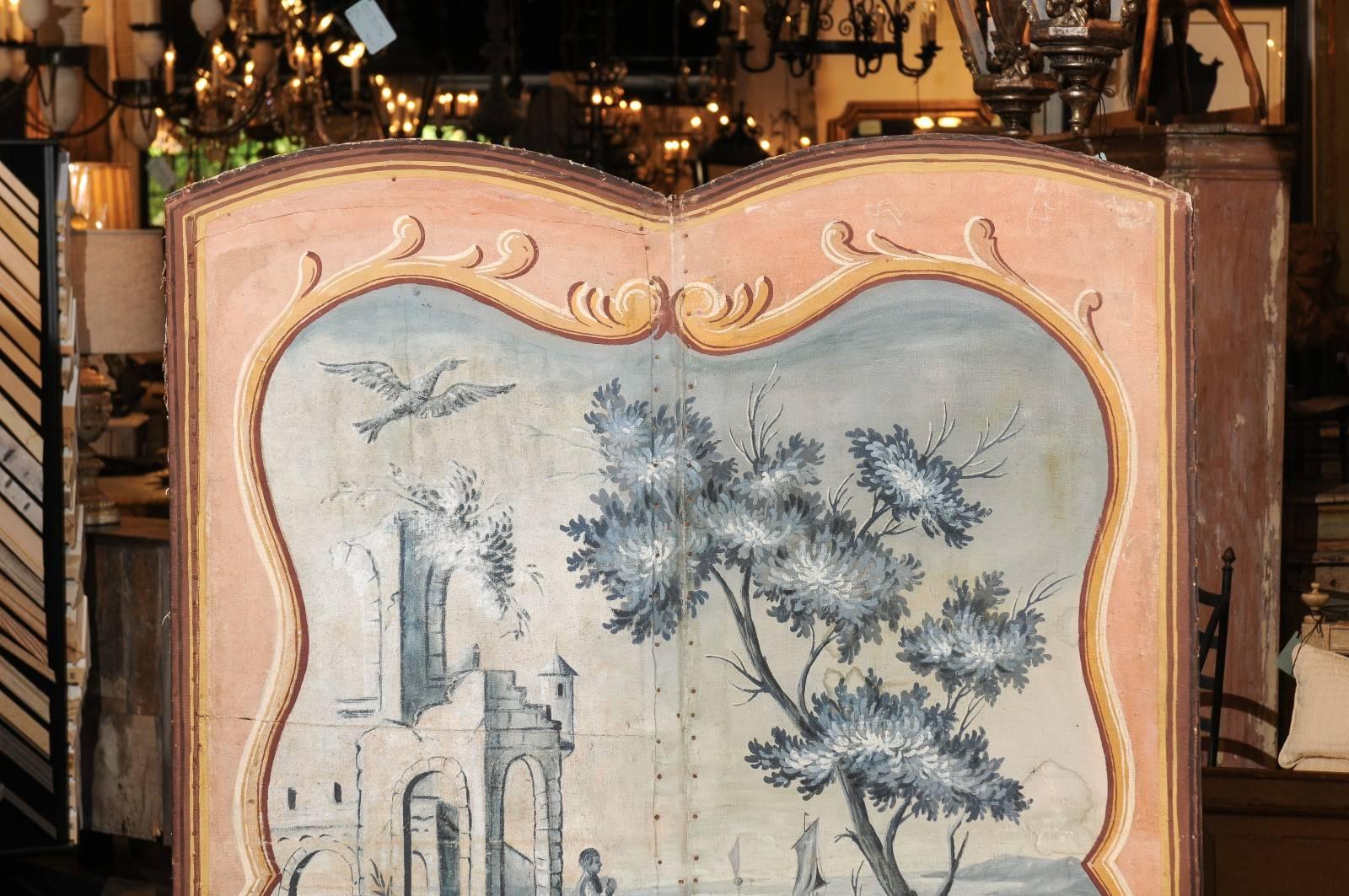 A pair of French grisaille pastoral hand-painted folding screens from the late 18th century. Each of these French screens features two panels adorned with an exquisite grisaille hand-painted scene set inside a trompe-l'oeil painted frame. These
