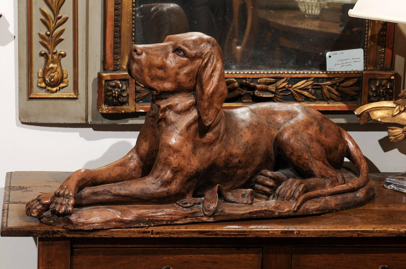 A French reclining terracotta hound dog sculpture from the early 19th century. This French animal terracotta sculpture features an exquisite depiction of a hound dog, obediently reclining on a shaped base. The general realistic treatment of the dog,