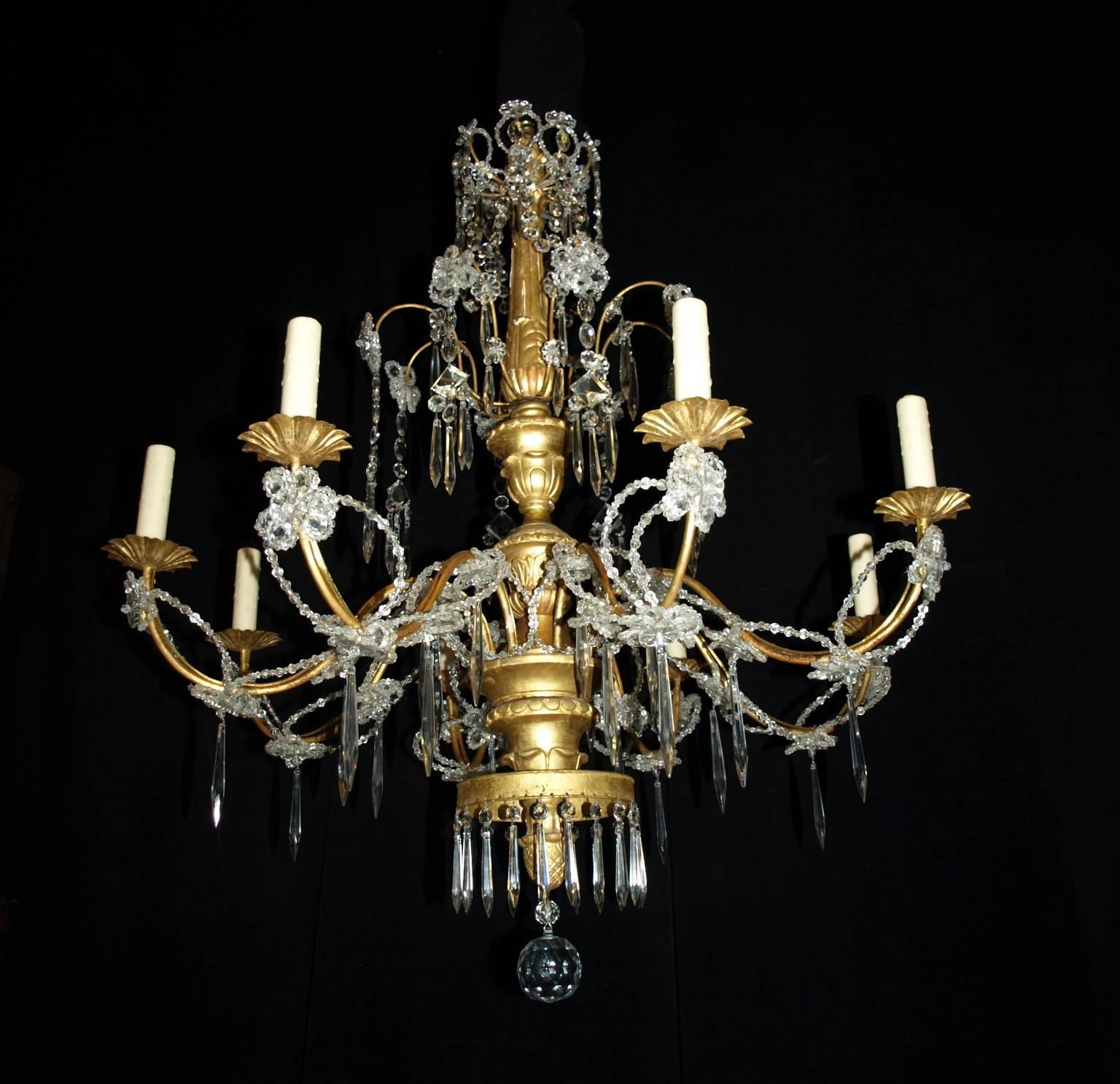 Very Fine gilded wood, iron, and crystal eight light chandelier.