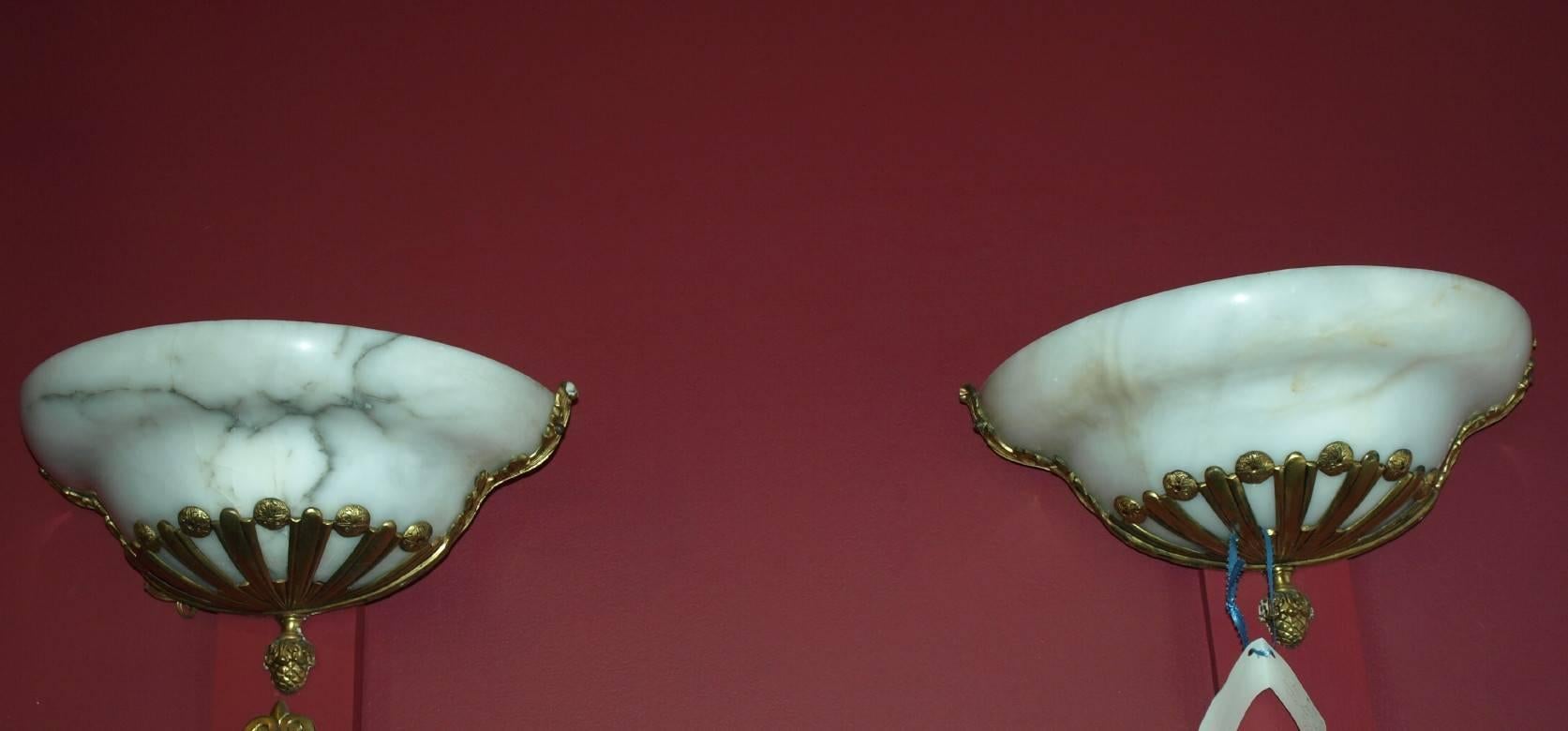 Nice pair of alabaster and gilt bronze sconces. Please notice one has more veining in the natural stone alabaster than the other. Both are mounted on gilt bronze frames.