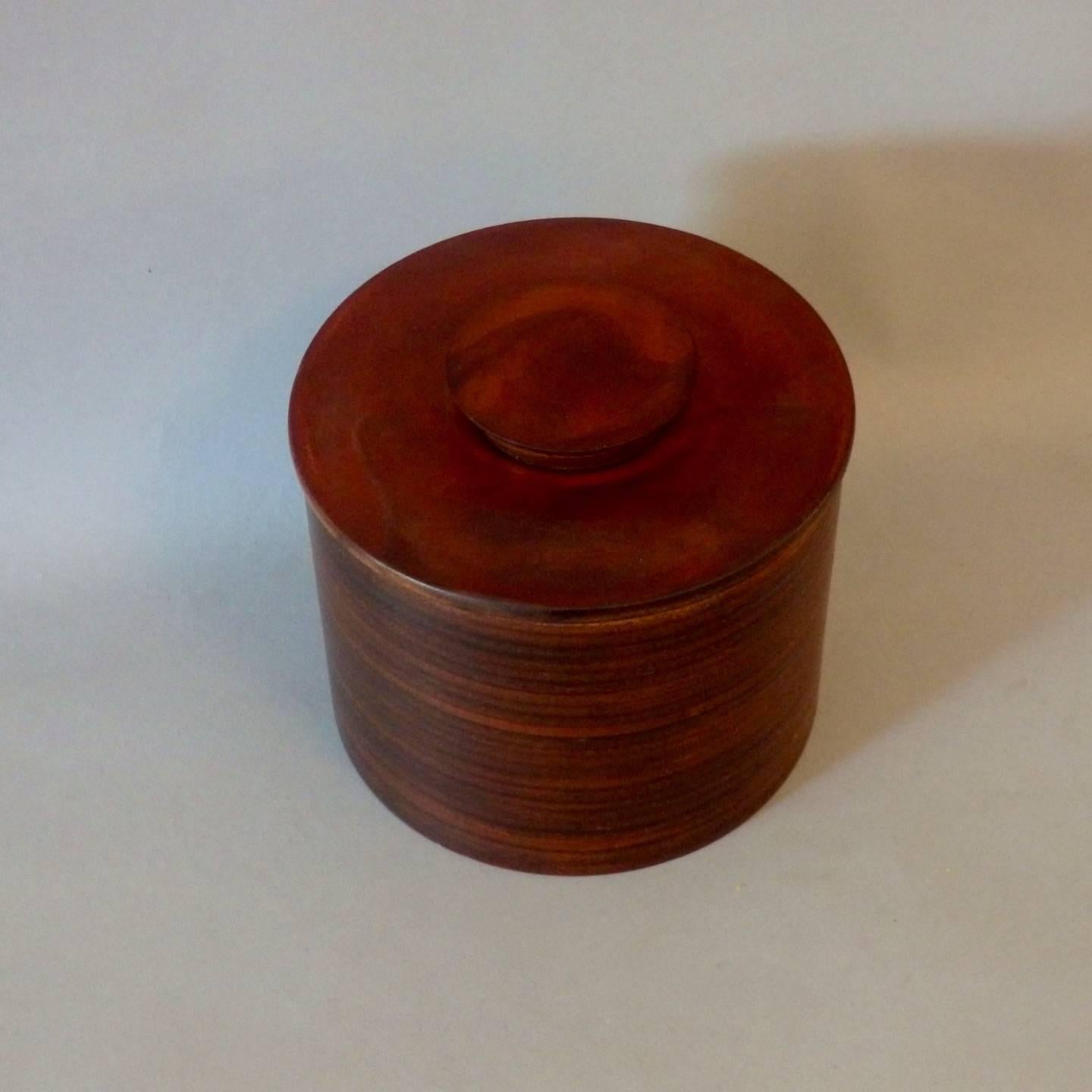Very nicely made stacked and laminated solid saddle leather forming a cylinder box with solid leather lid and finial handle.