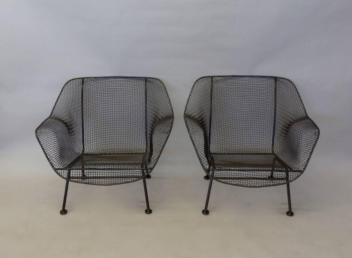 Pair of the large John Woodard wrought iron with steel mesh seat lounge chairs. Fresh glides have been installed on the feet. Recently powder coated in a bronze finish.