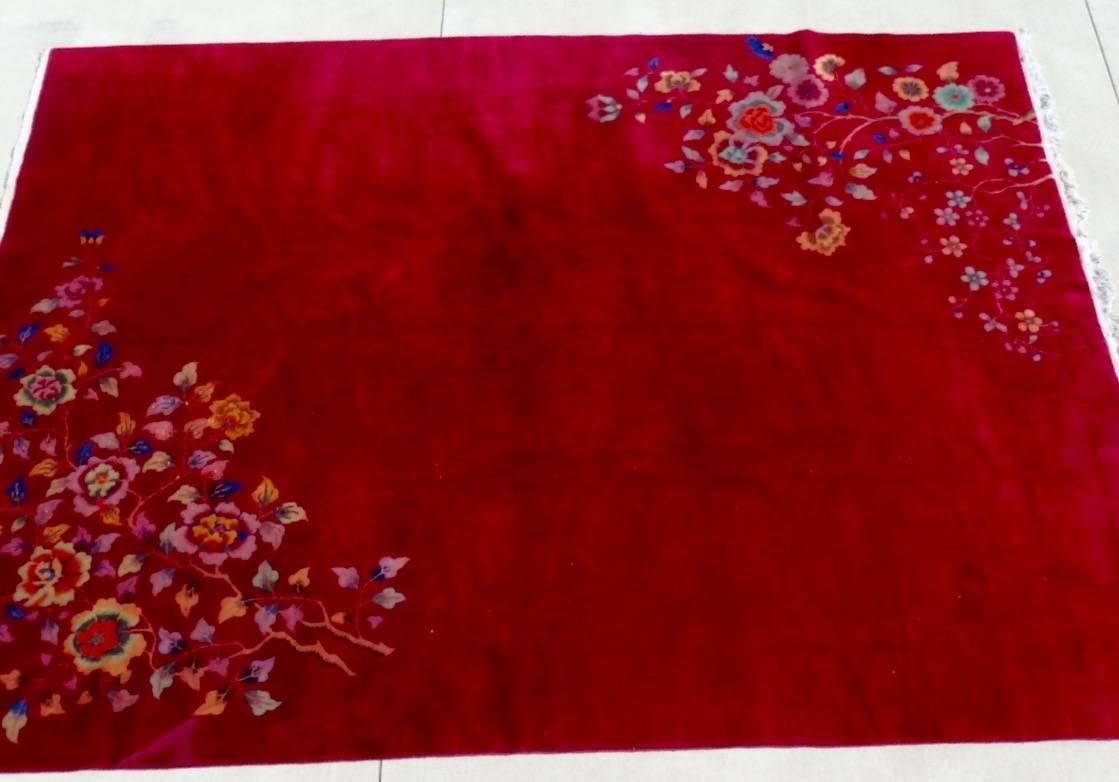 Deep red field Chinese Deco Nichols rug. Bright colored floral design in two corners. One or two small discolorations (shown) but truly excellent overall condition.