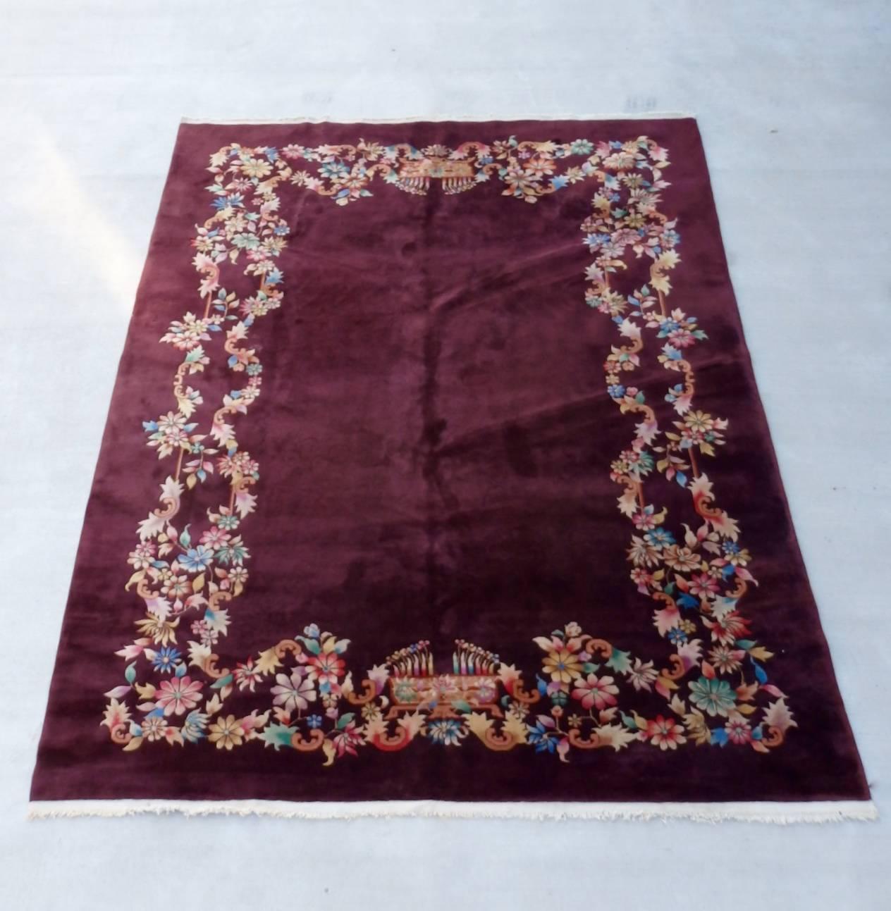Beautiful Nichols wool rug in excellent condition. Field is a deep sable brown. A mix of claret red wine and black coffee. Colorful intertwined floral border. There is also a tracing ghost floral pattern throughout the brown field.