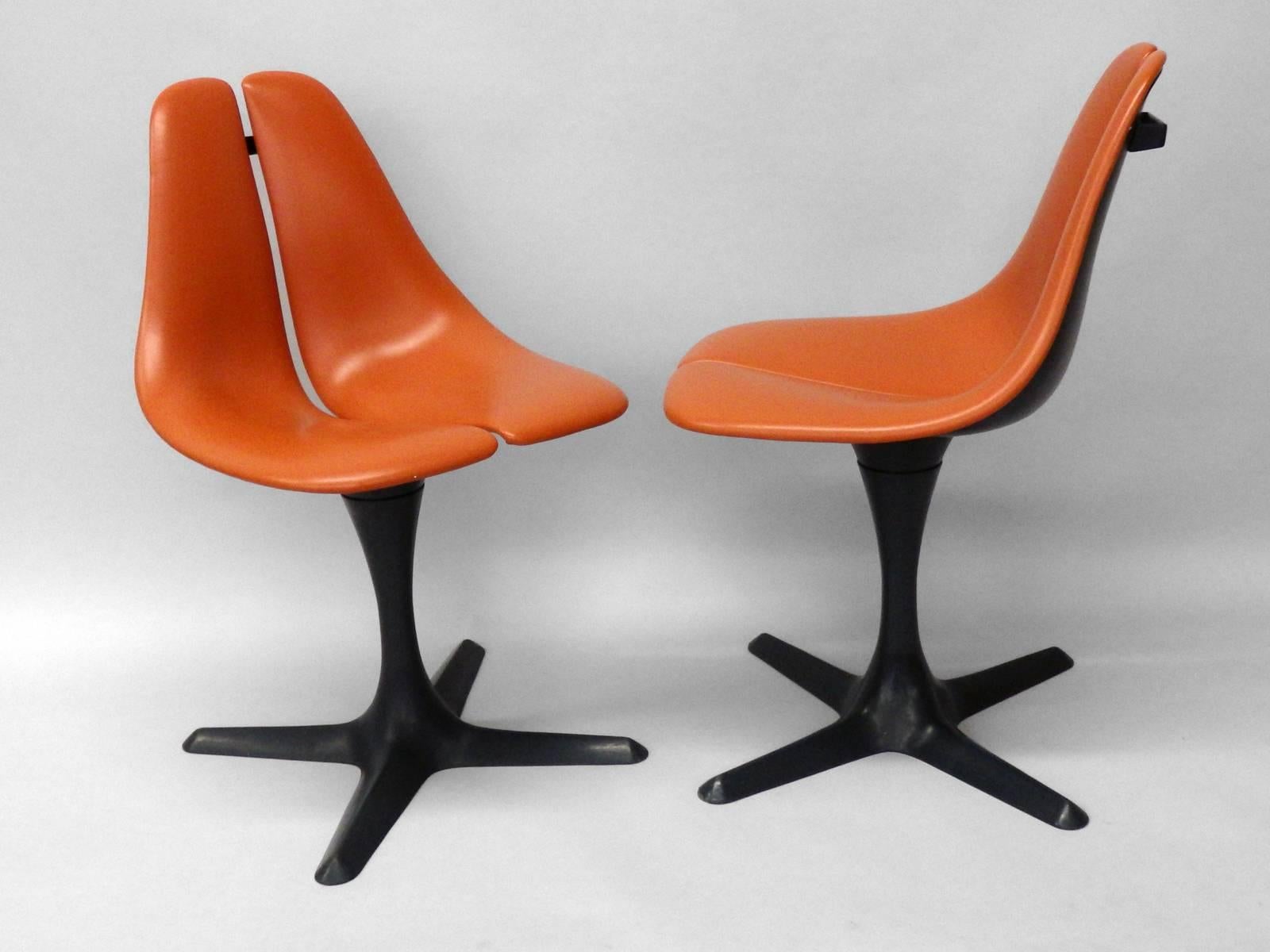 Not the usual Saarinen Knoll knock off chair from Burke . This pair of pedestal chairs are a more original design . Orange vinyl on fiberglass split seat supported on 