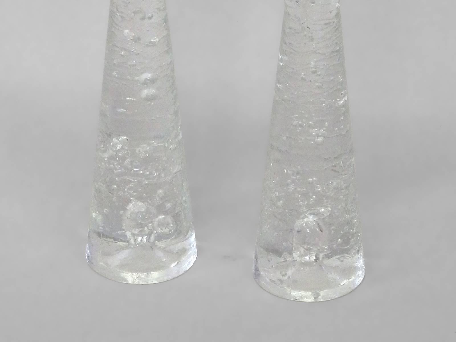 Pair of glass candlesticks designed by Timo Sarpaneva for Littala Finland . Solid clear glass in a pinched waist form with internal controlled bubble detail .