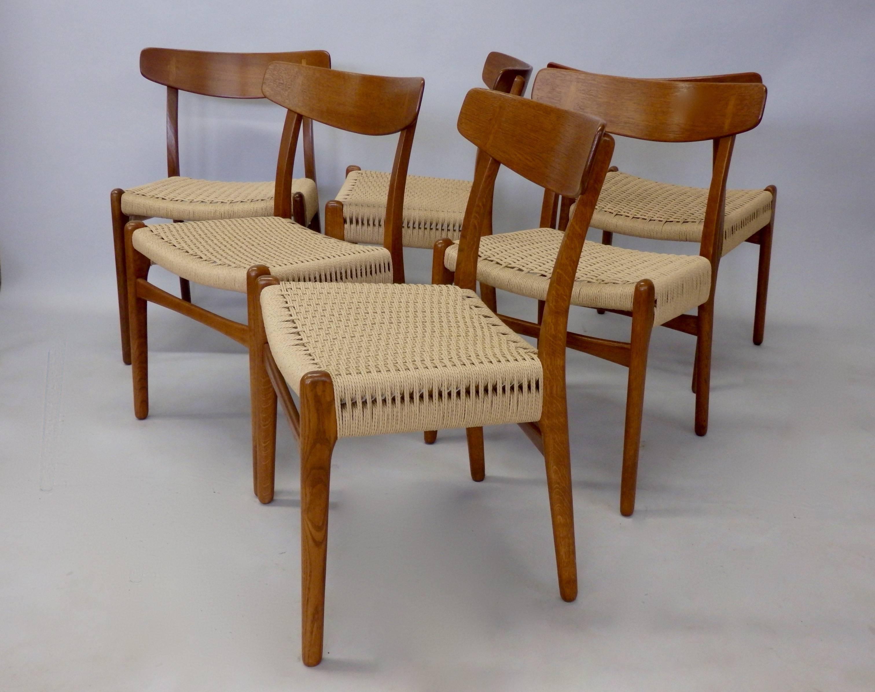 Beautifully and fully restored Hans Wegner teak and oak dining chairs. Built by Carl Hansen Odense, Denmark. Wood frames have been refinished, Danish rope seats have been correctly replaced on each chair.