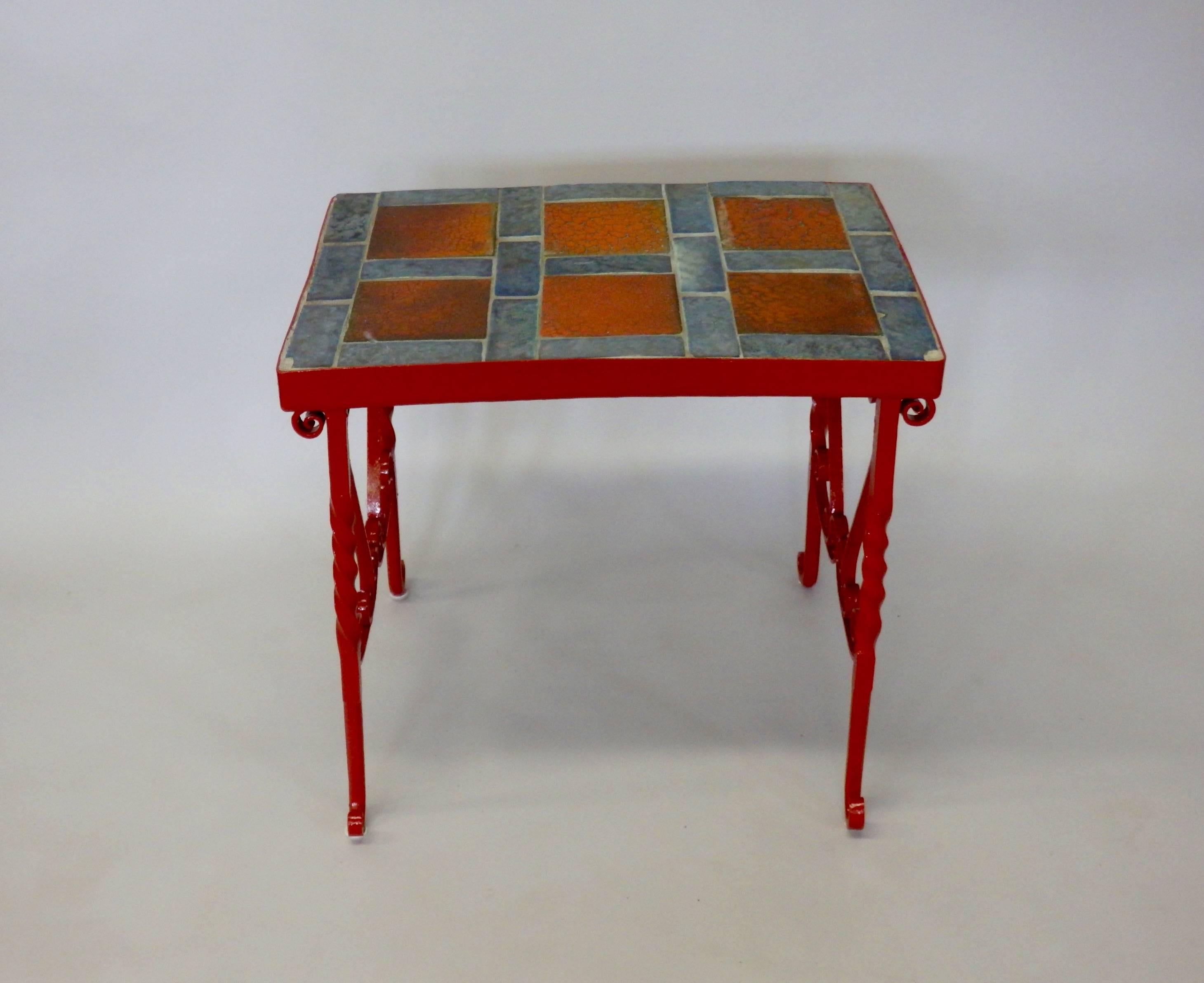 Appears to be studio built Folk Art style table. Table made up with California tiles some chipped before being set in cement top on heavy wrought iron legs. Legs painted red.