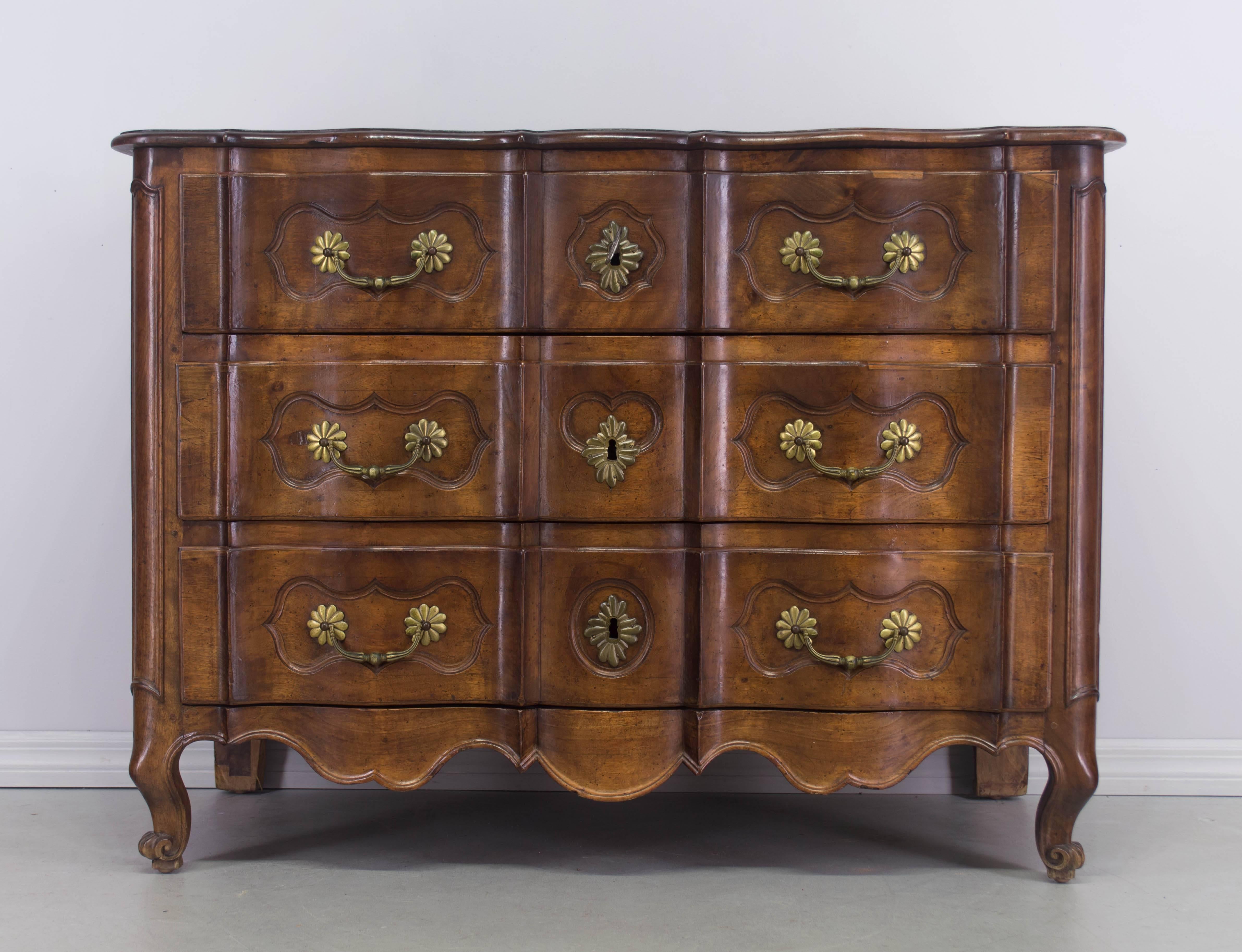 18th century French Louis XV commode or chest of drawers, made of solid walnut with an arbalette (crossbow) front. Raised panels on the sides and curved front corners. Three dovetailed drawers with original bronze pulls. Locks in working order with