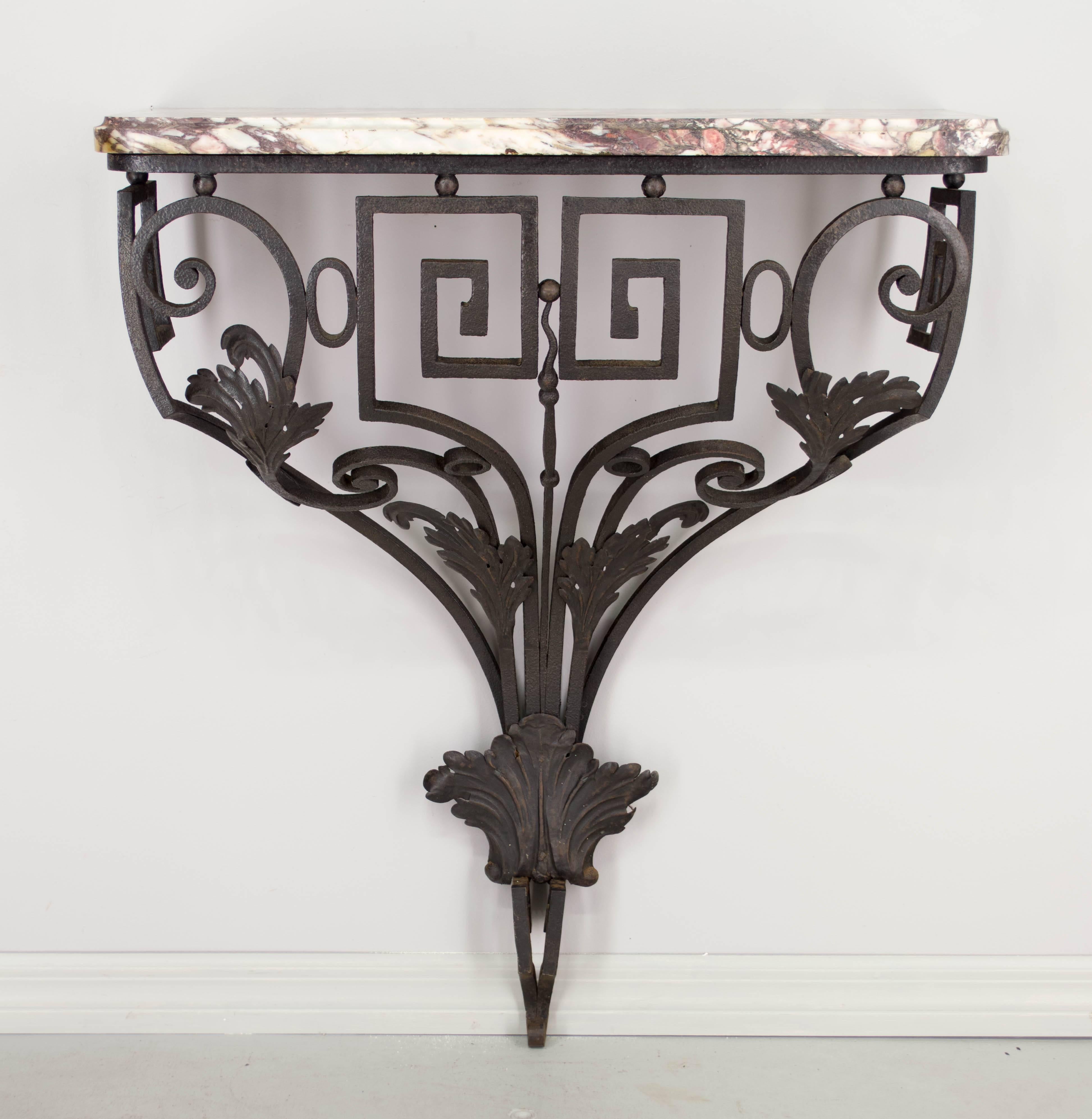  A Louis XVI wrought iron console with marble top. Classic Greek key design with scrolls and acanthus leaves. Beautiful color marble with burgundy and grey veining. Requires two screws to be fastened to the wall.  All Original. Please refer to