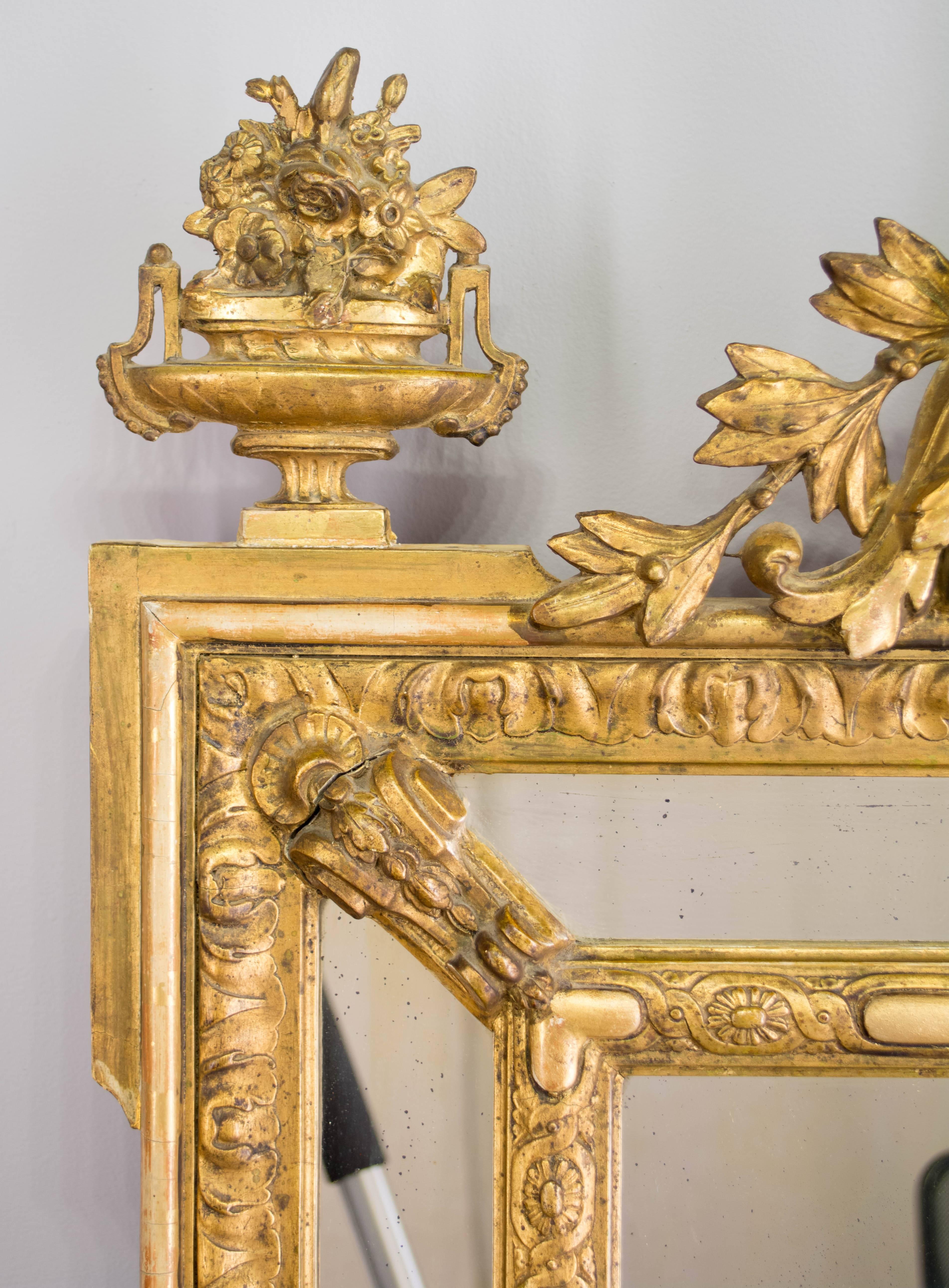 19th century Napoleon III gilded mirror. Elaborately detailed crest with carved putti and flower baskets. Bright gilt with minor touch-ups. Original looking glass has old silvering streaks. 
More photos available upon request. We have a large