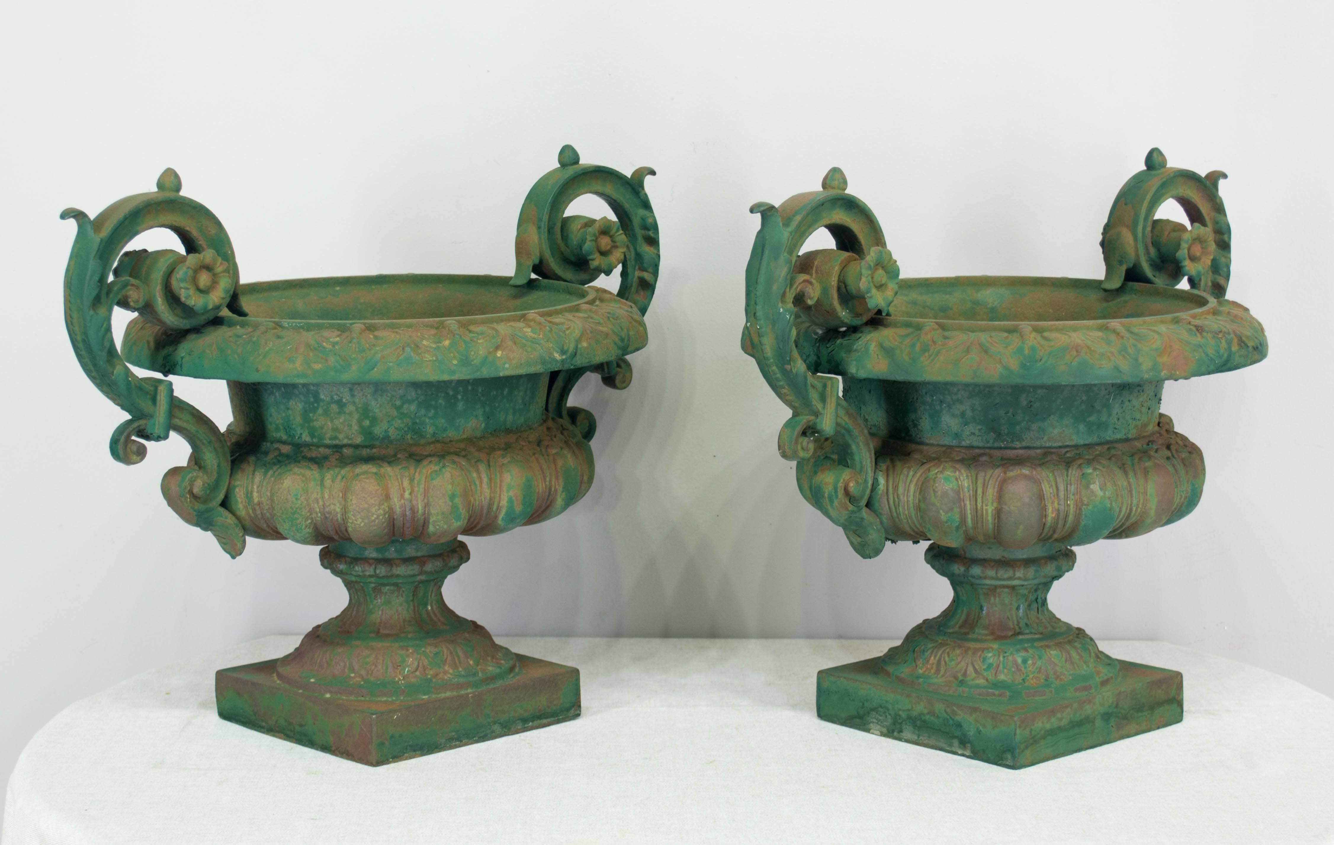 Pair of 19th century French cast iron urn planters, with original weathered green painted patina. Nicely cast details, especially on the double handles. Base: 7.25" square urns: 14.5" diameter. Weight: 42 lbs. each. 
More photos available