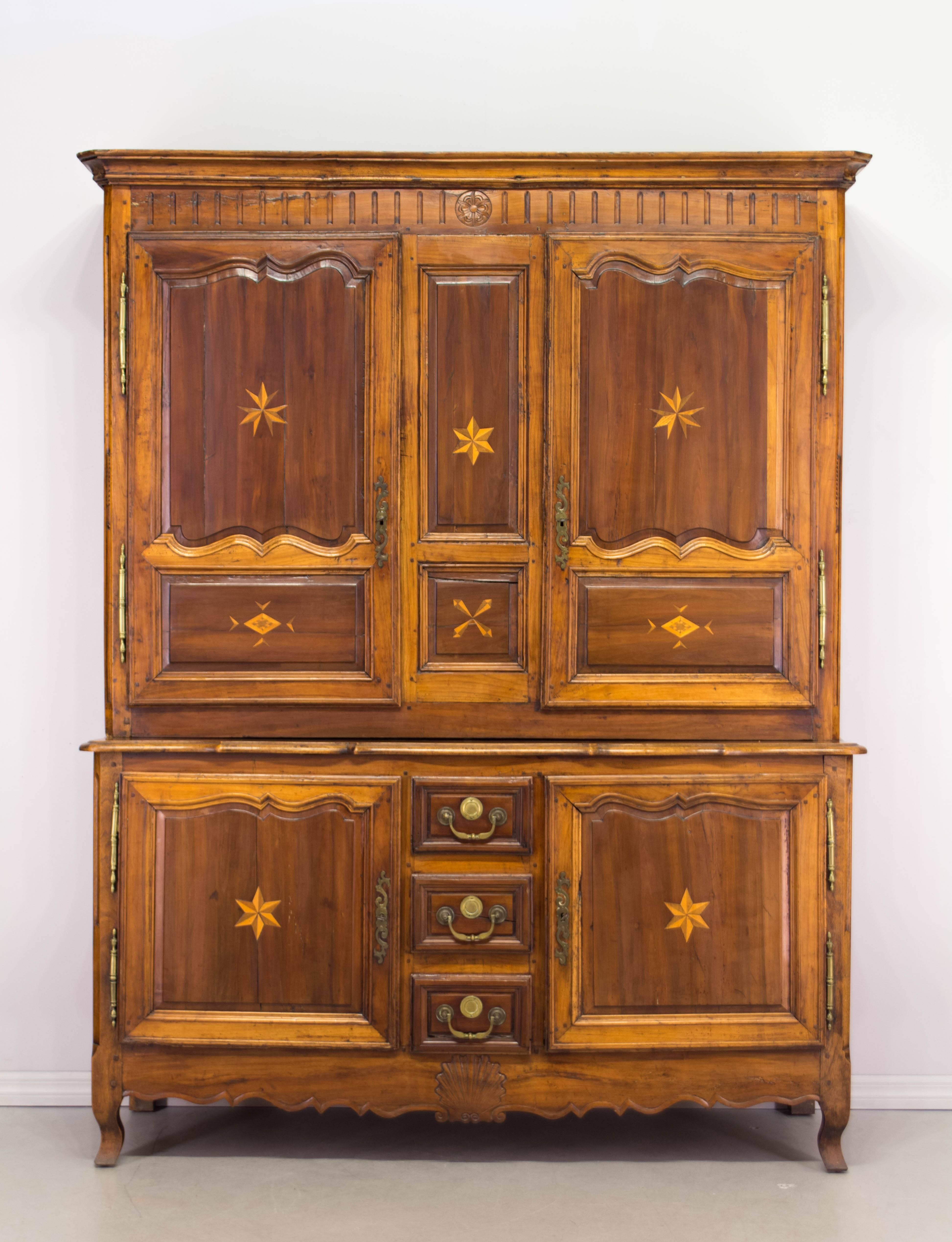 18th century Louis XV buffet à deux corps from the East of France made of cherry and walnut with carved panels. Nicely decorated with inlaid stars and pinwheels. Ample storage, with adjustable shelves. Interior retains some old fabric lining.