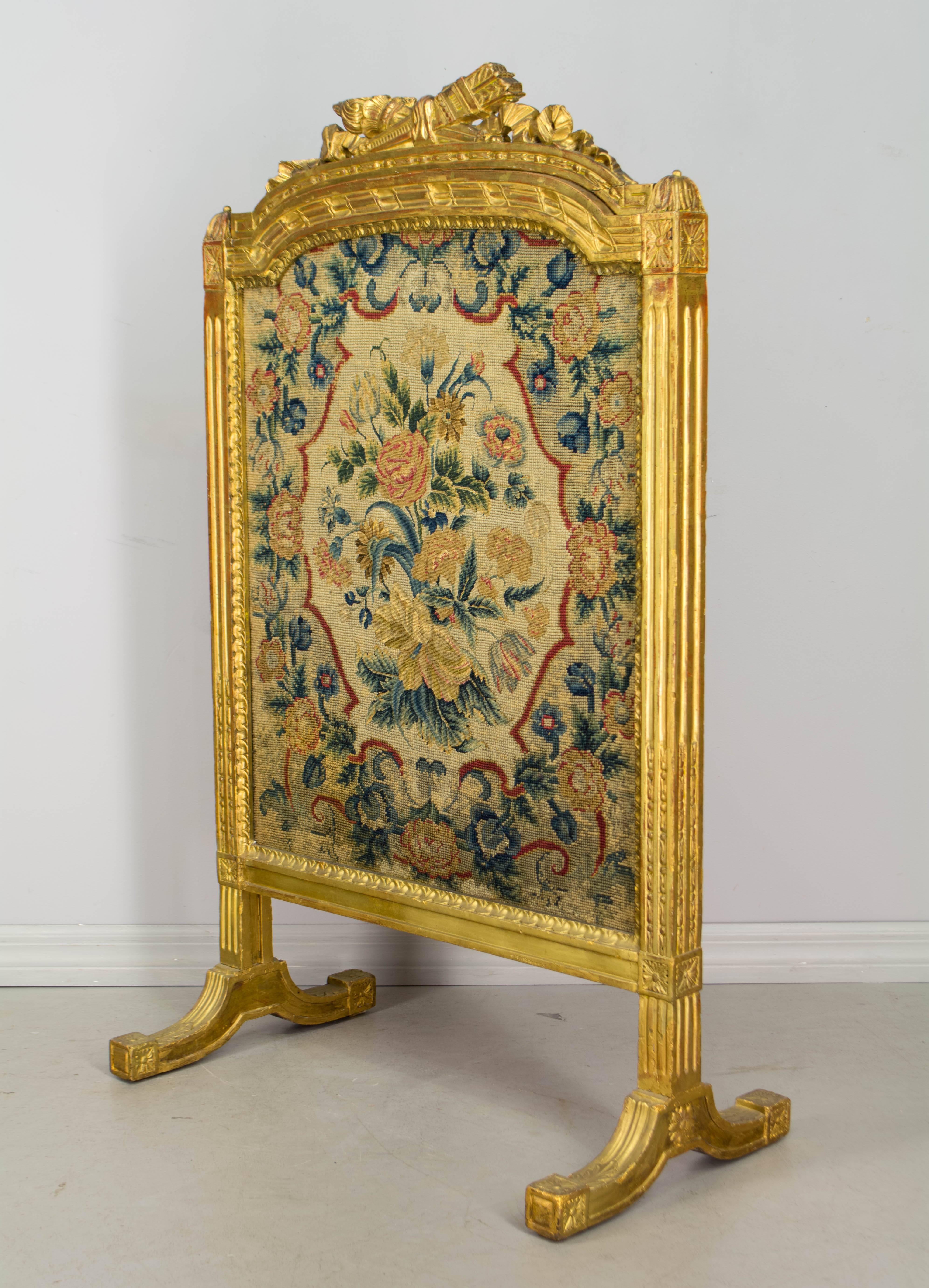 19th century Louis XVI style fire screen with carved and gilded wood frame and petit-point tapestry. Gilt is nice and bright, with some restoration and touch-ups throughout. Beautiful floral tapestry is in excellent condition with vivid color.