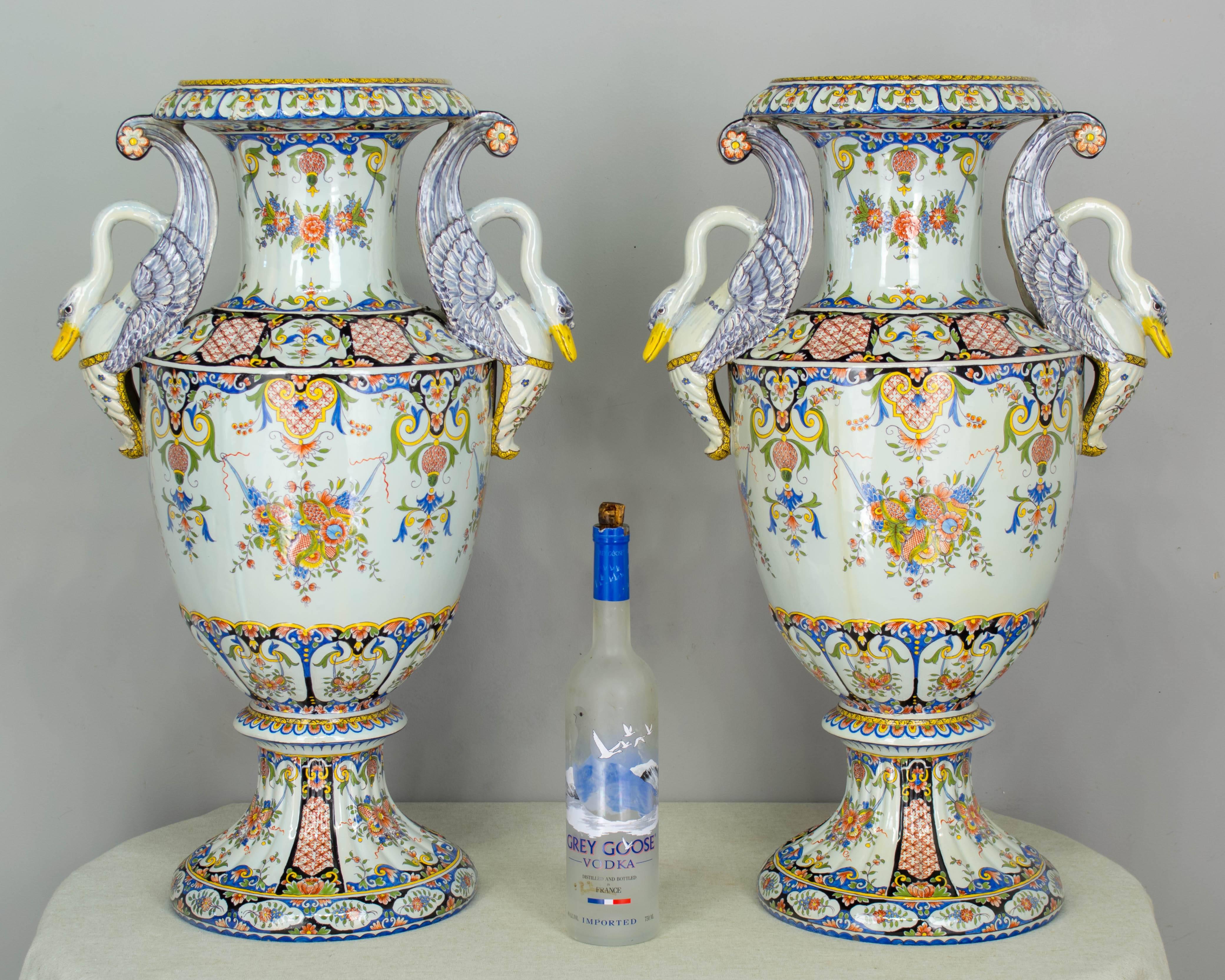 An exceptional pair of large 19th century French faience urns from Desvres, by Fourmaintraux-Freres. Beautiful hand-painted floral decoration and sculptural swan handles. Elegant form with nice proportions. In almost mint condition with the beak of