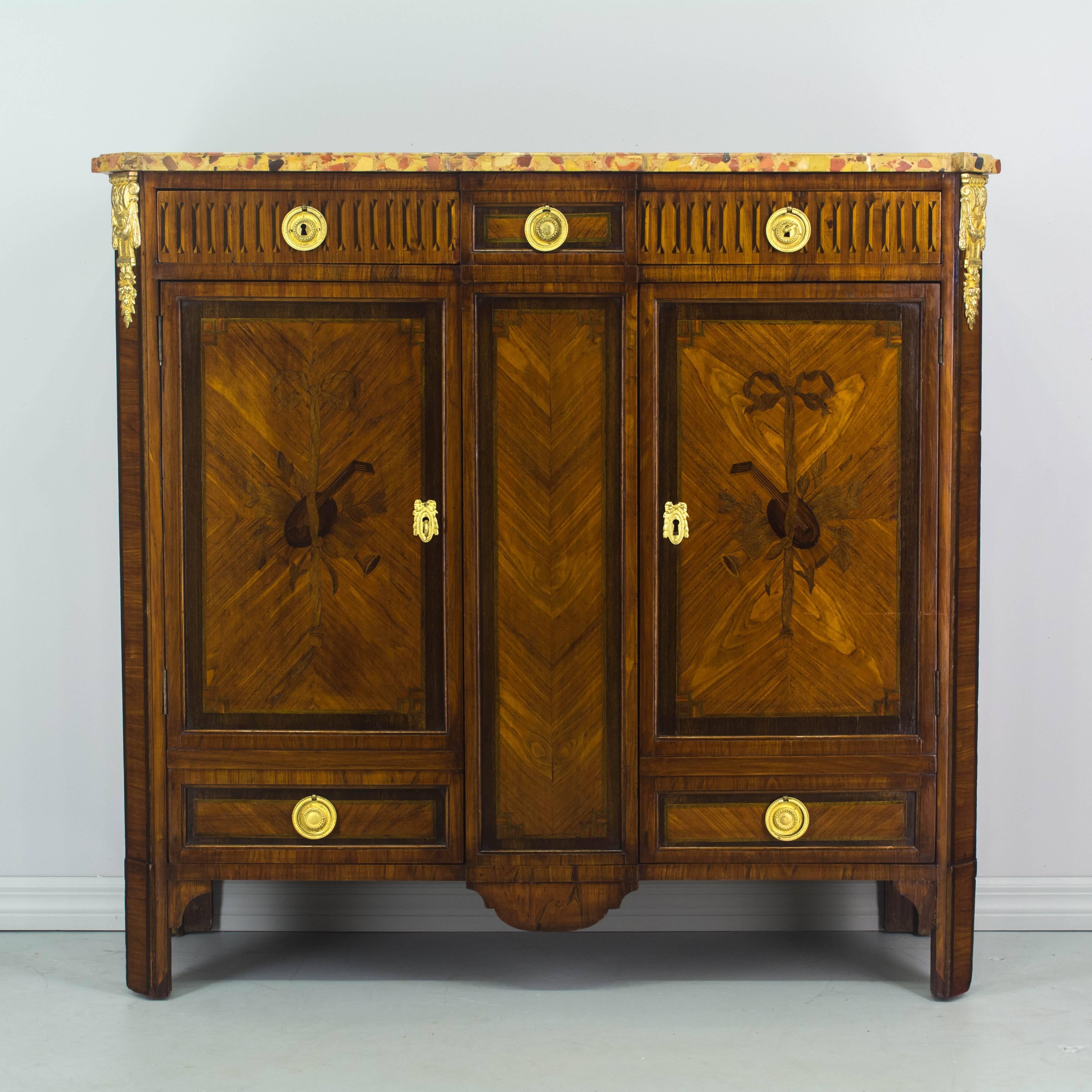 A 19th century Louis XVI style Parisian buffet with two dovetailed drawers and opening to two interior adjustable shelves. Fine marquetry work using various wood veneers including walnut, maple, and mahogany with oak as a secondary wood. French