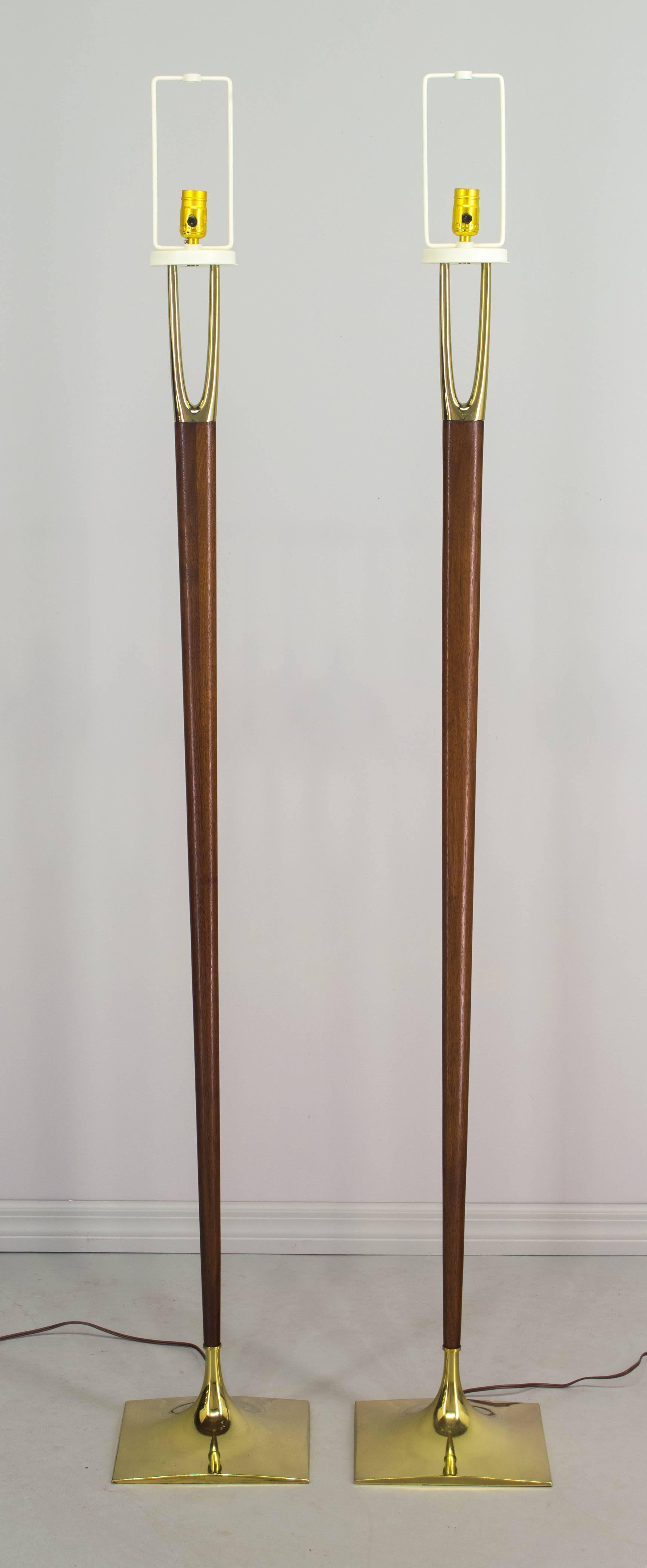 Pair of iconic, sought after Mid-Century Modern floor lamps designed by Gerald Thurston and made by the Laurel Lamp Company. Solid walnut center post with beautiful wood grain. Brass-plated wishbone shaped prong at top and a brass-plated base.