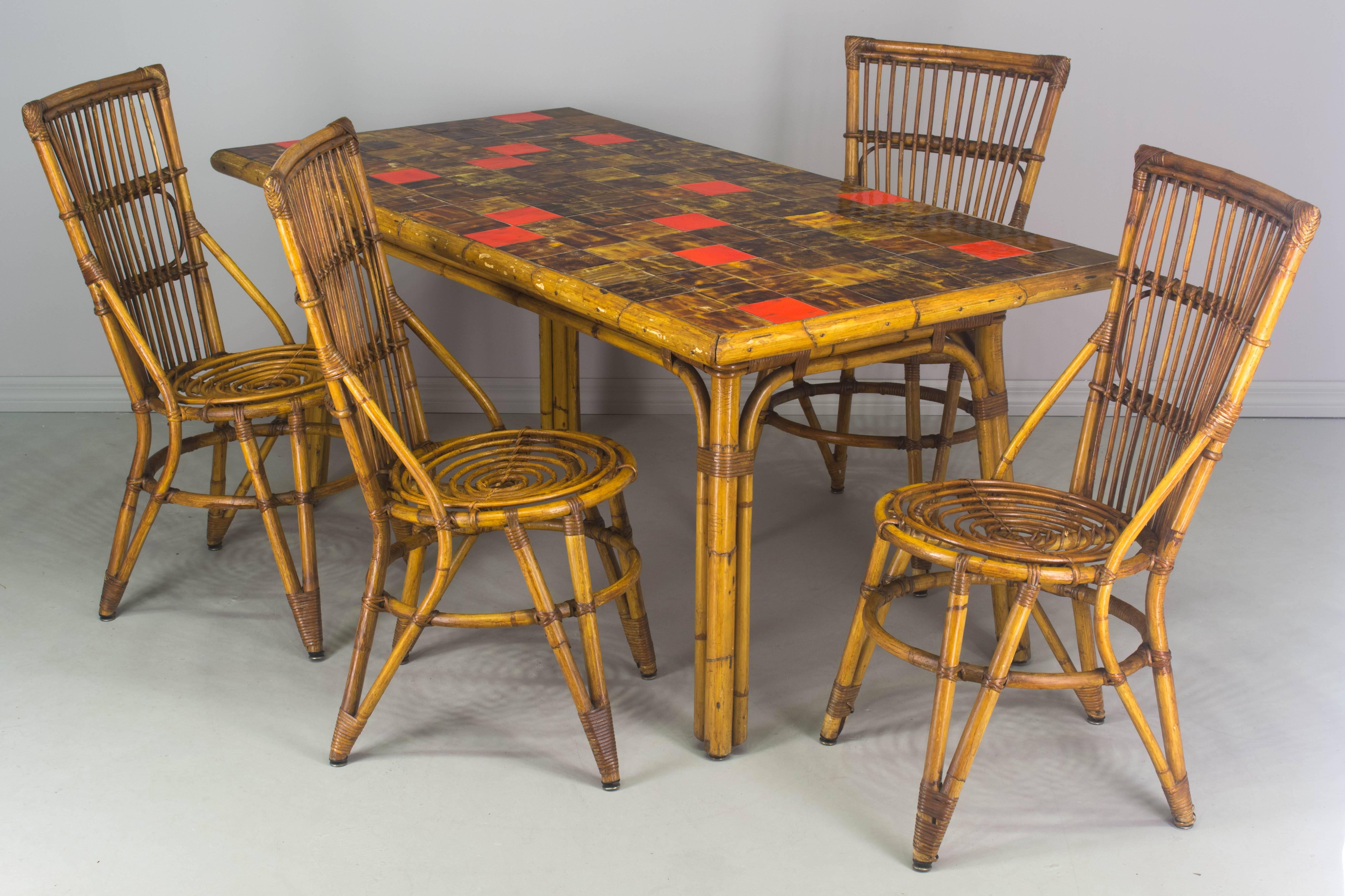 French Mid-Century Riviera style rattan dining table and chair set. Table top has glazed ceramic tiles from the South of France. Four chairs are comfortable and sturdy. A chair pad (not included) may be added as shown. 
Table: 66