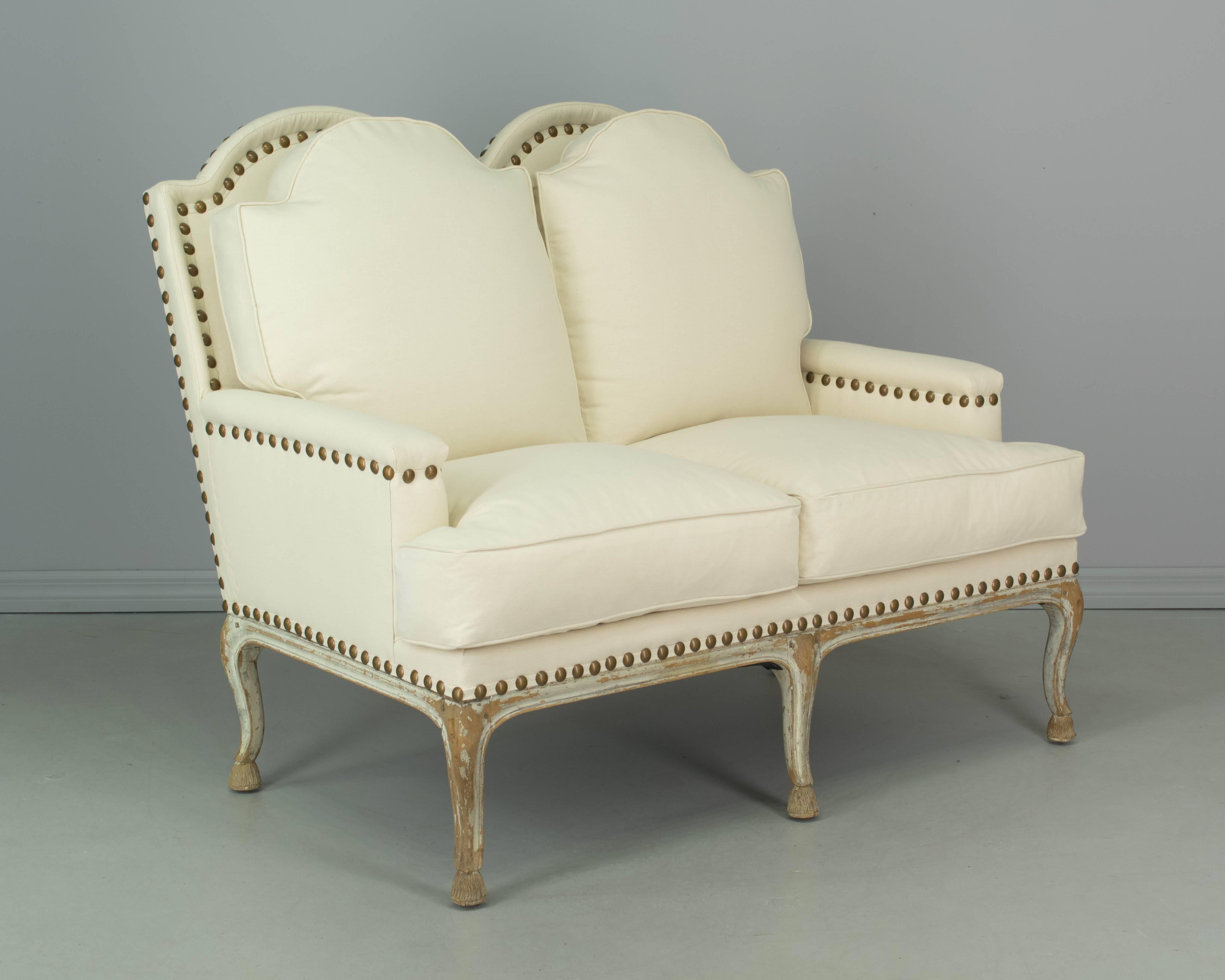 19th century French Louis XV style settee made of beechwood with pegged construction. Sturdy five-leg frame with some of the original paint remaining. Reupholstered in neutral cotton canvas fabric with decorative brass nailhead trim. Wrapped down