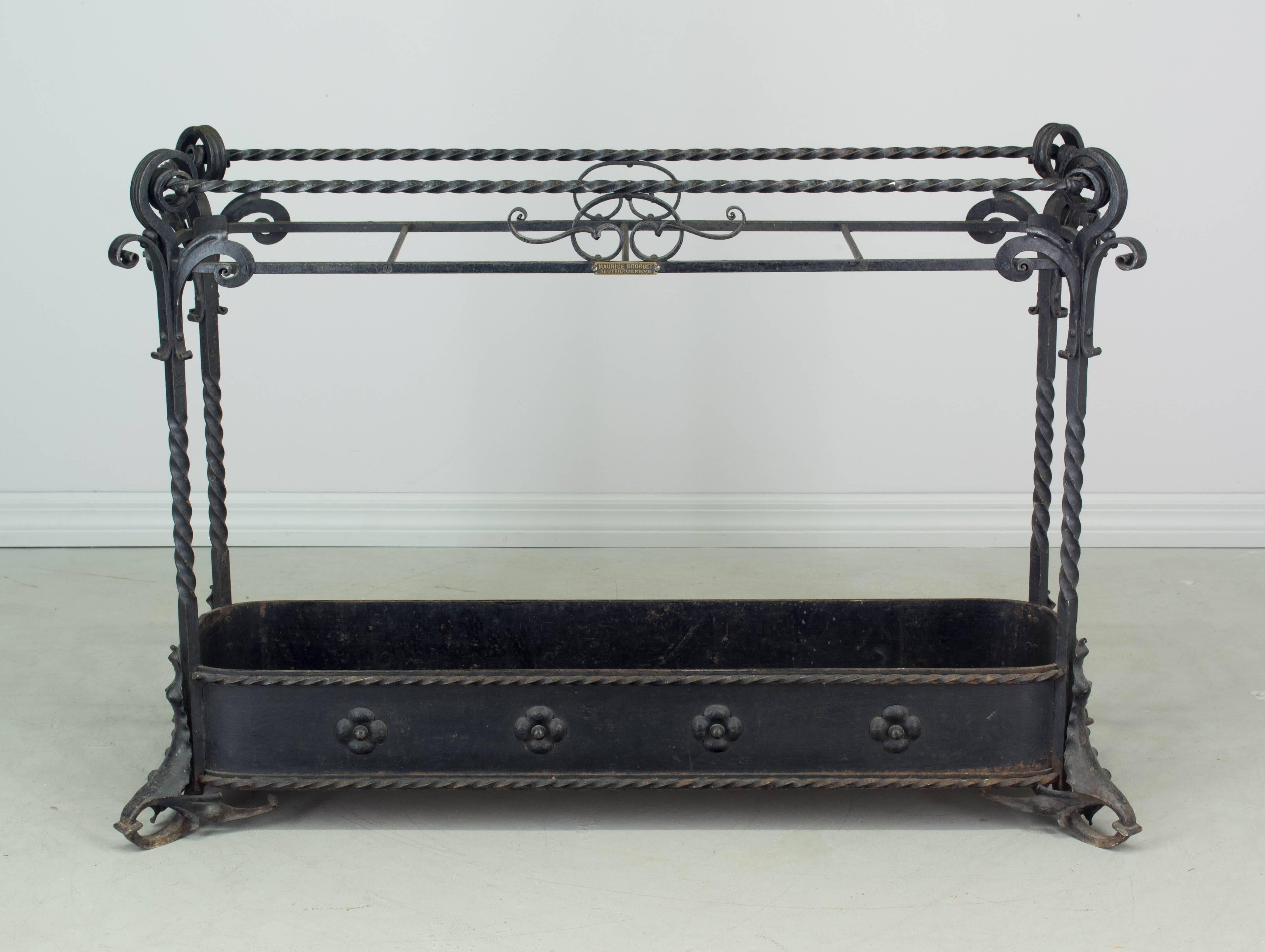 A wrought iron umbrella stand from a Swiss hotel. Excellent craftsmanship with elaborate scrolls and twists, flowers along the bottom and leaf forms at the feet. Metal plaque with the ironworker's name reads: 