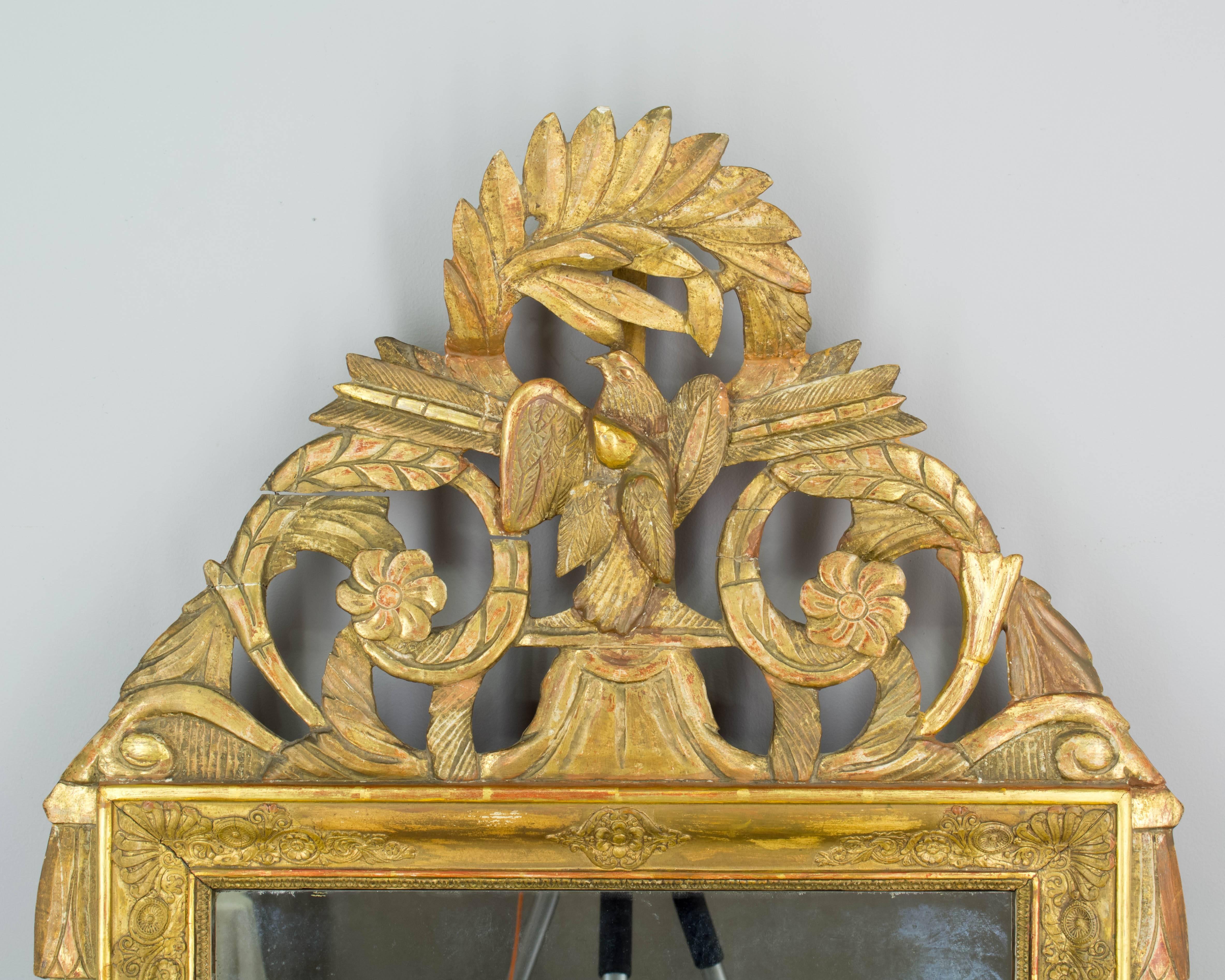 19th century Louis XVI style Provençal bridal mirror with gilt and gesso frame. Beautiful carved wood crest with lovebirds and floral decoration. Original looking glass with old silvering. Bottom right decoration has been replaced. Crest has natural