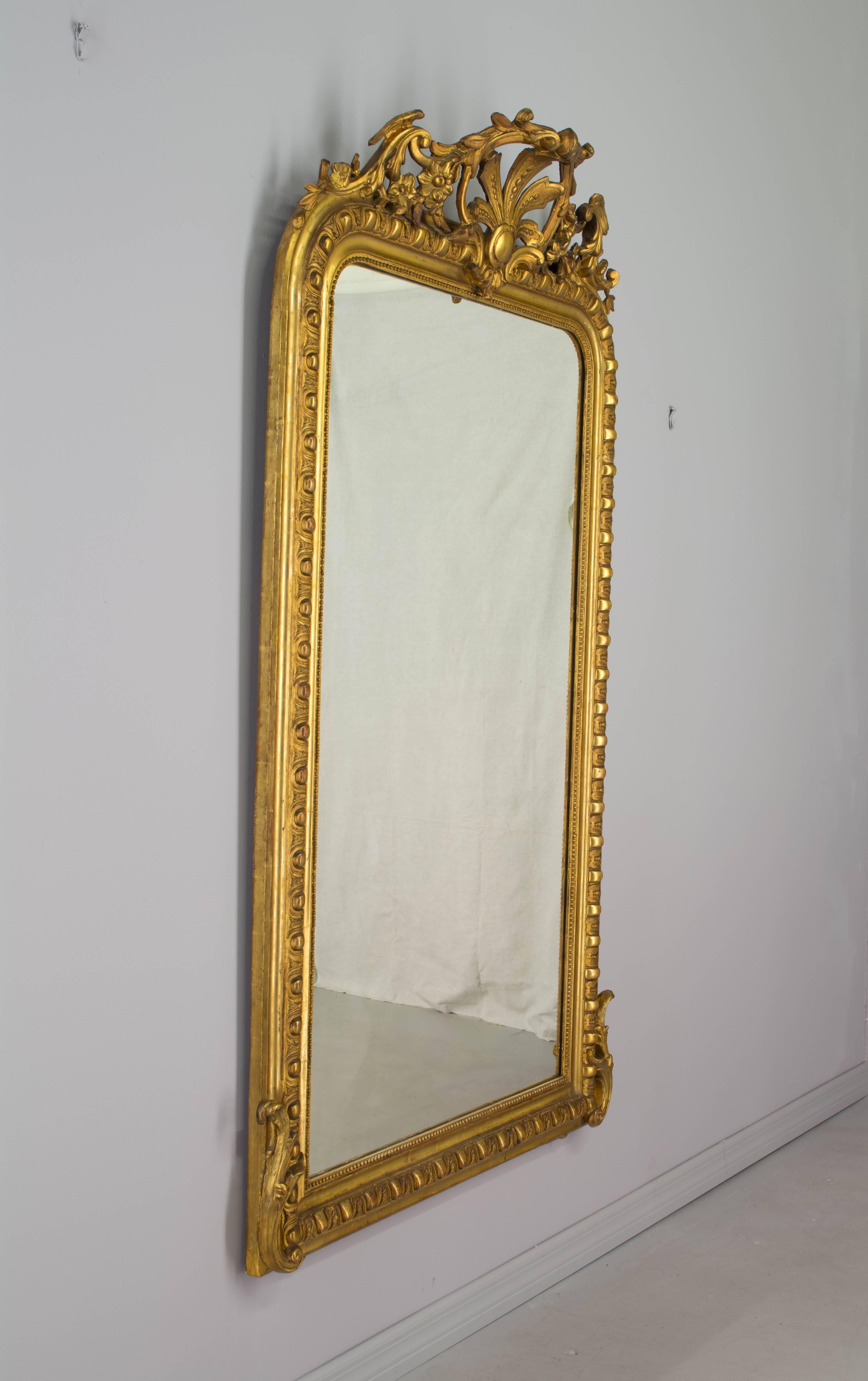 19th century French Louis-Philippe gilded mirror with carved crest and corner details. Original looking glass. Minor restorations to carvings and touch-ups to gilt.
Measures: 67" H x 37.5" W x 2" D (8" deep at crest).
More photos